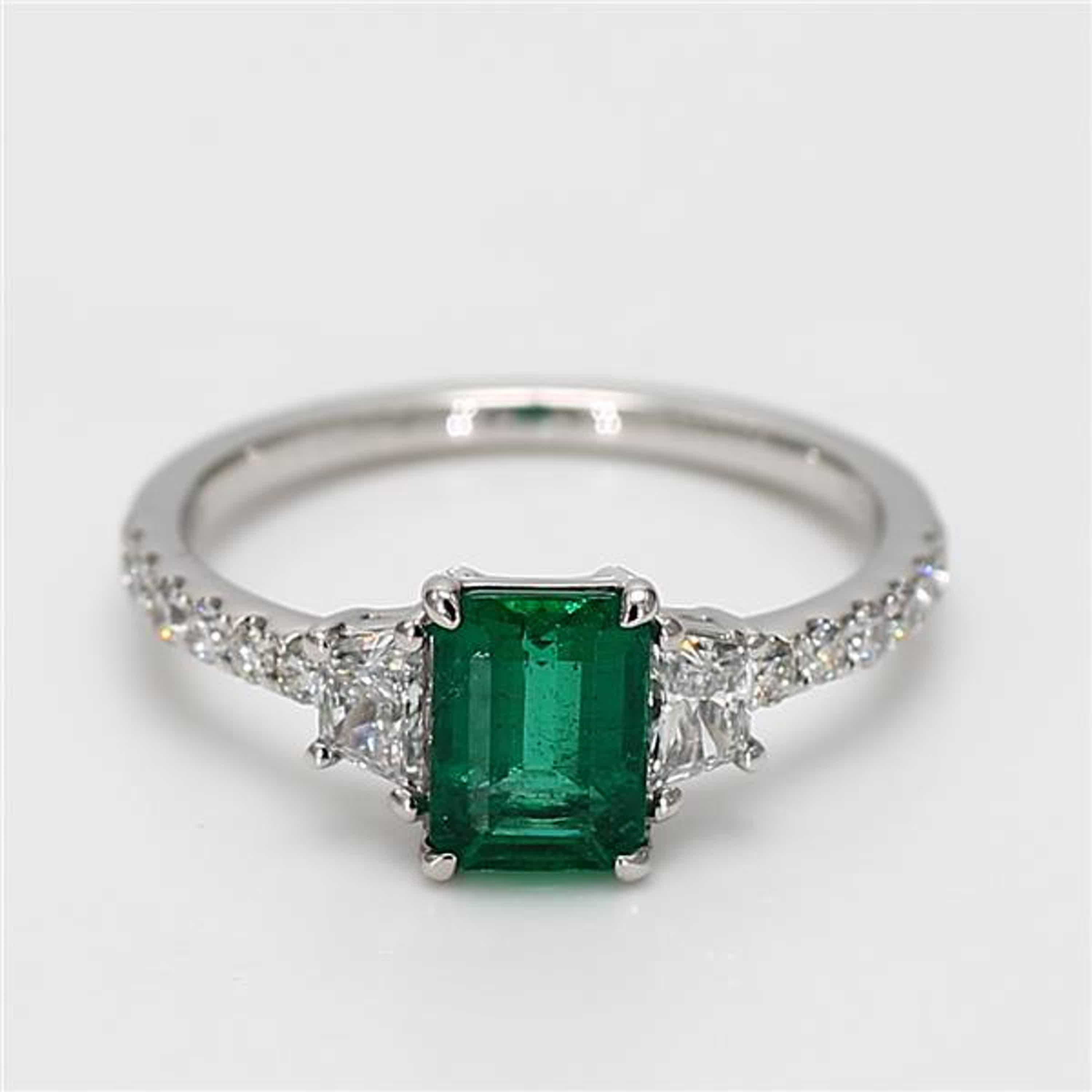 RareGemWorld's classic emerald ring. Mounted in a beautiful 18K White Gold setting with a natural emerald cut emerald. The emerald is surrounded by natural round white diamond melee as well as natural taper baguette cut white diamonds. This ring is