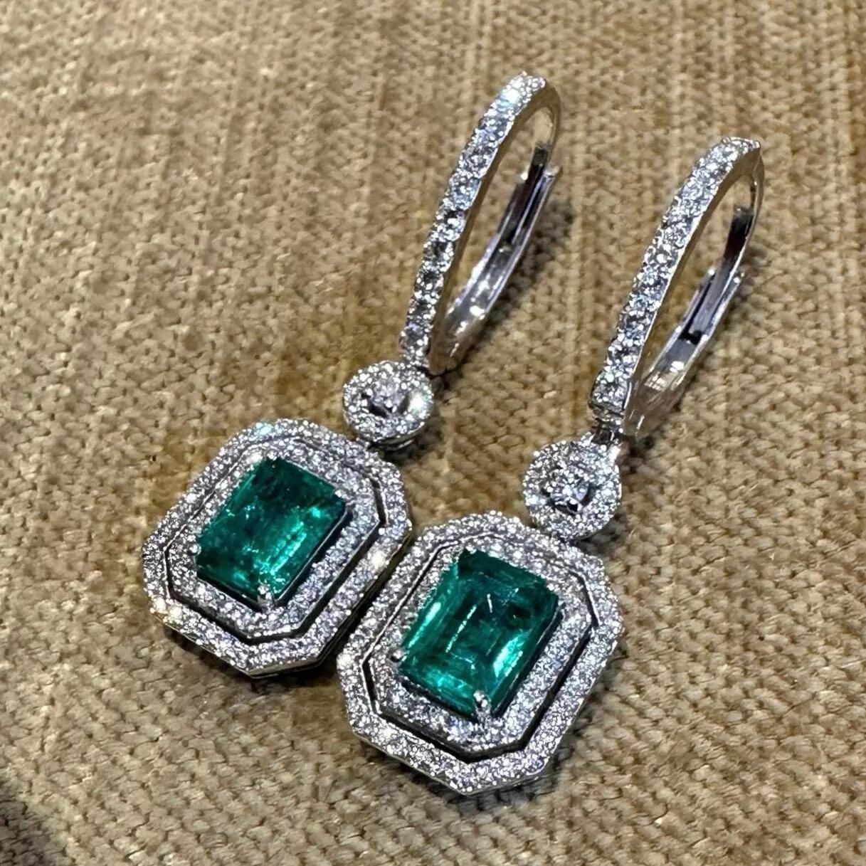 Natural Emerald and Diamond Drop Earrings in 18k White Gold

Diamond and Emerald Earrings feature 2 Green Emeralds surrounded by 2 rows of Round Brilliant Diamonds pave set in 18k White Gold.

Total emerald weight is 1.70 carats.
Total diamond