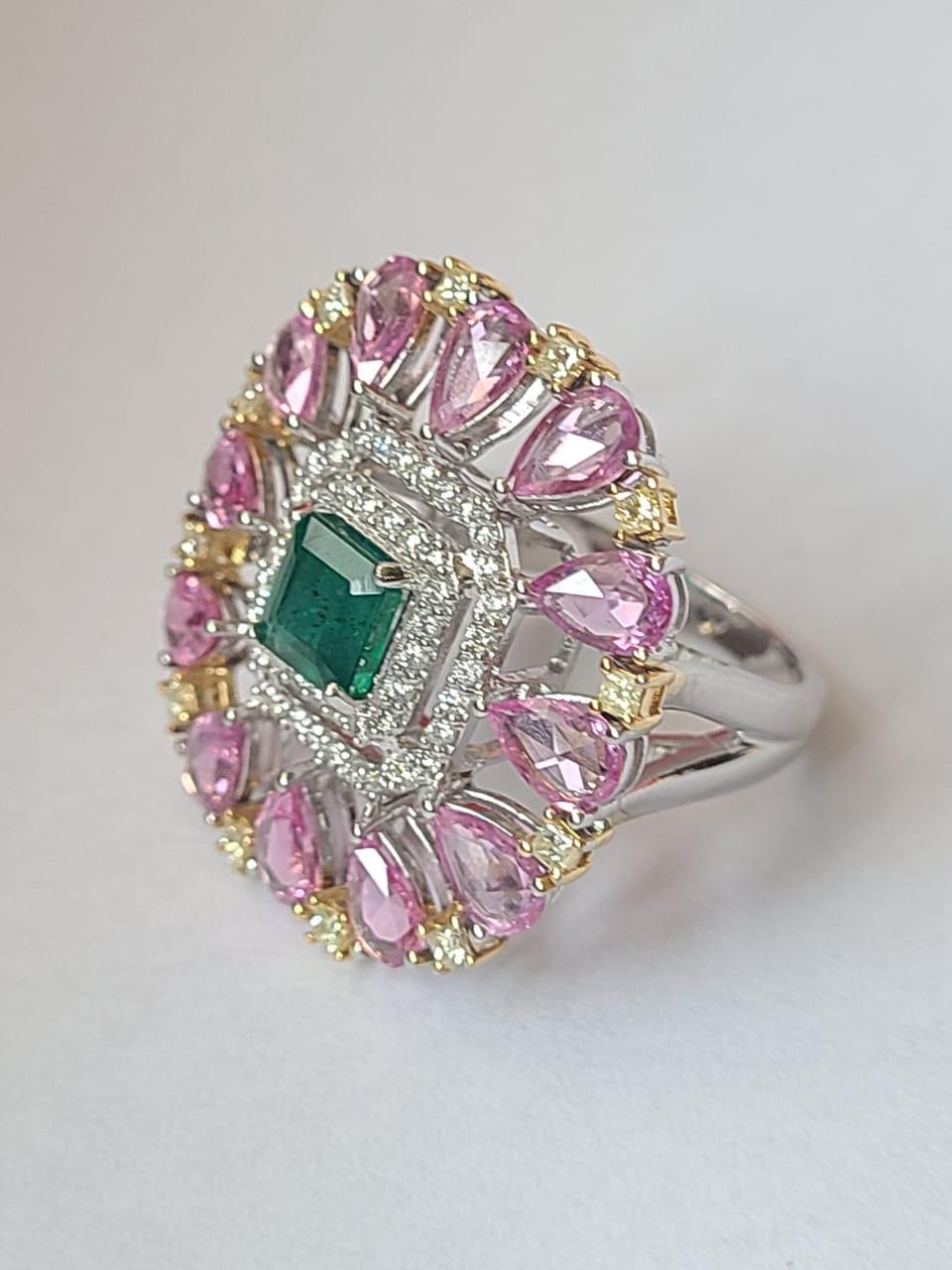 A very gorgeous and one of a kind, Emerald & Pink Sapphires Cocktail Ring set in 18K White Gold & Diamonds. The weight of the Emerald is 1.20 carats. The Emerald is completely natural, without any treatment and is of Zambian origin. The weight of