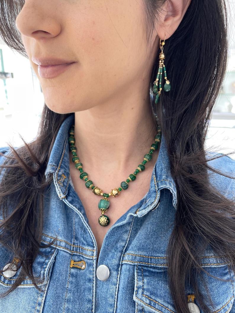 Wir stellen Ihnen unsere exquisite Anhänger-Halskette mit geschnitztem Smaragd vor. Dieses atemberaubende Schmuckstück besticht durch eine Reihe von runden Cabochons, Rondellen und aufwendig von Hand geschliffenen Smaragden, von denen jeder