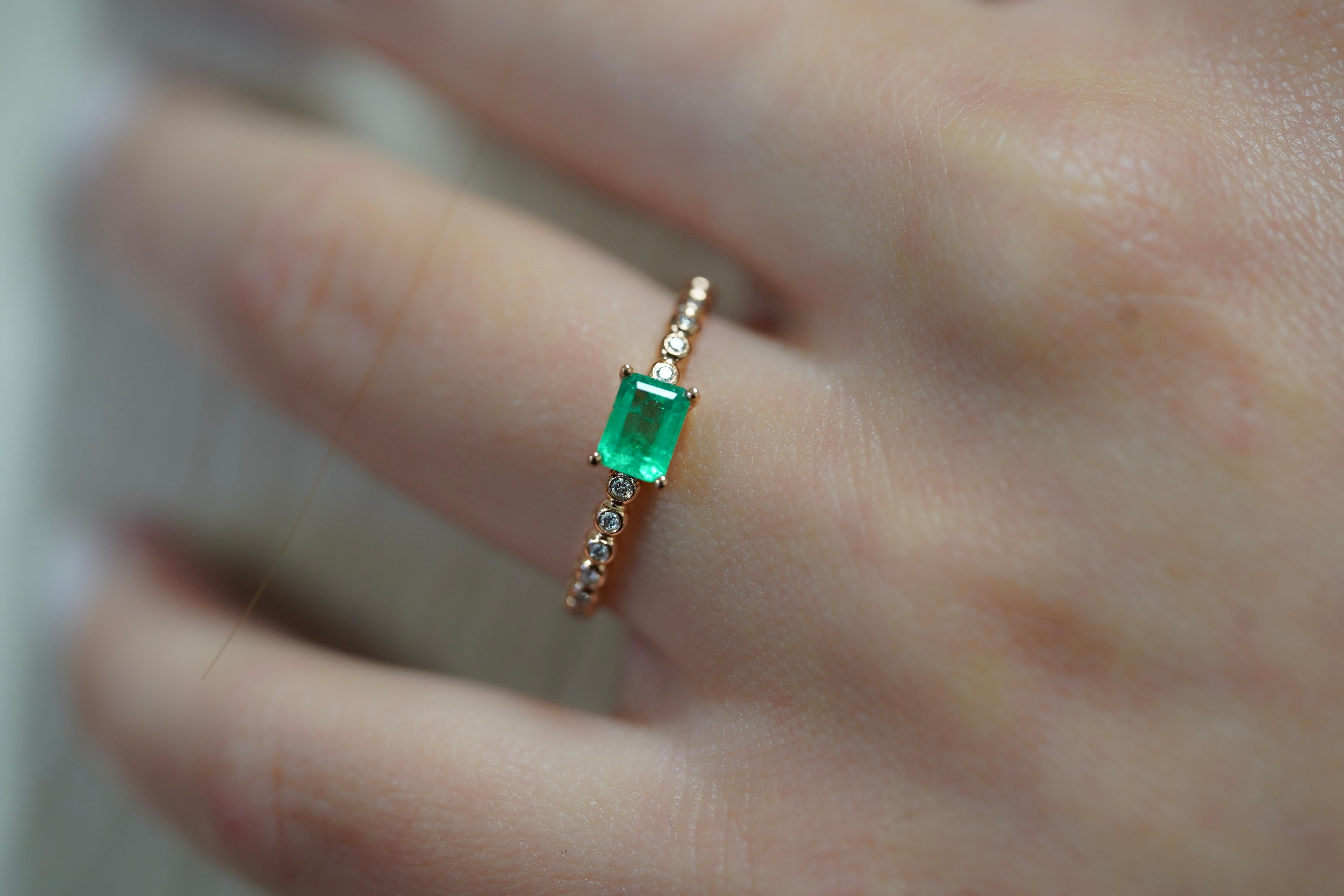 18K rose gold Emerald and Diamond ring. Set with natural gemstones and glistening 18k solid gold. Dainty 2mm thin width and east west setting makes it ideal as a stacked band or wearing alone. The center stone bears a richly saturated Colombia Green