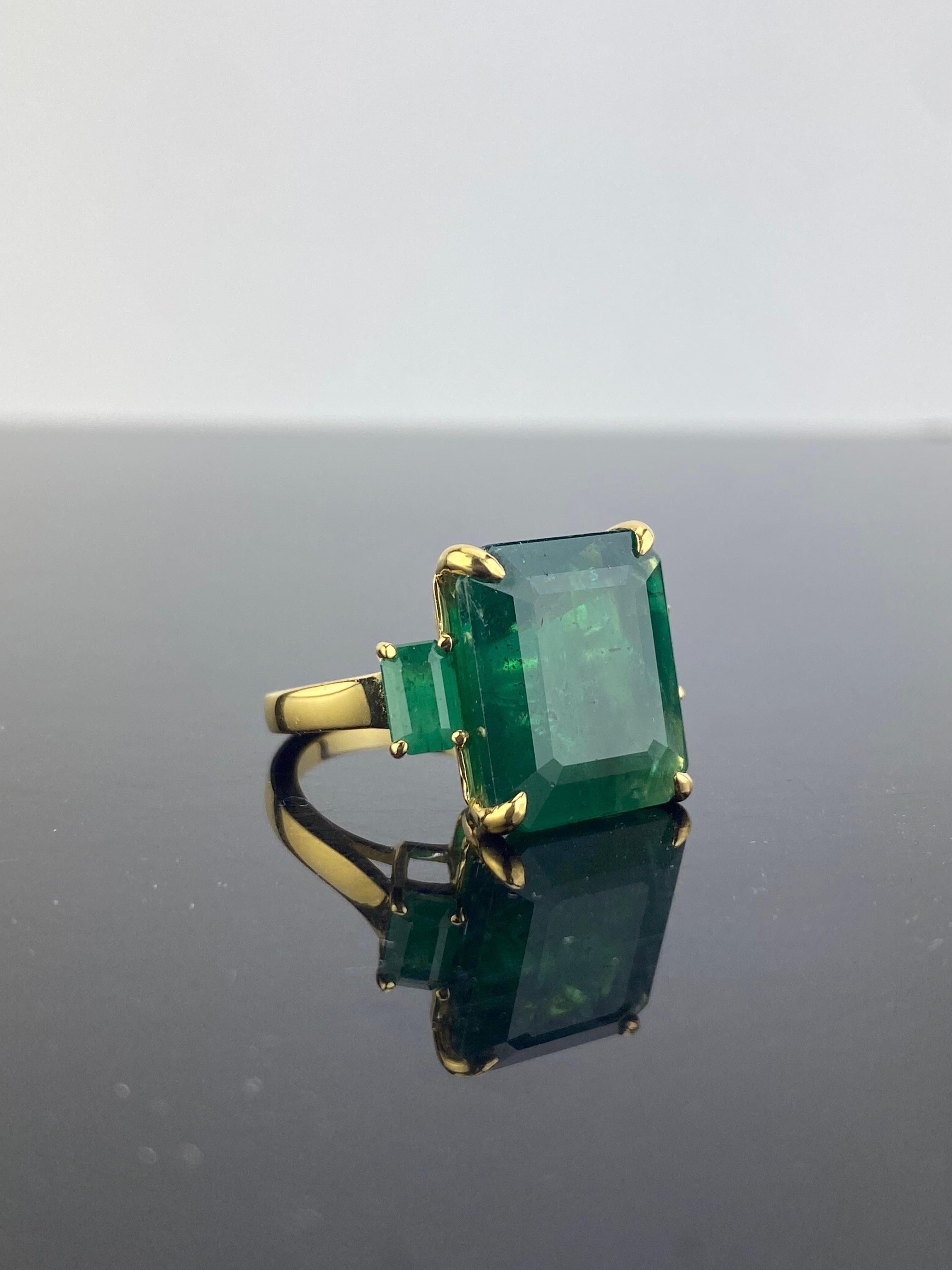 This ring displays the work of 3 natural Zambian Emeralds casted in solid 18K Yellow Gold, the centre stone is 14.01 carat and the side stone is 1.21 carats, all vivid green color. The ring is sized at US 7, but can be resized. 
We ship worldwide