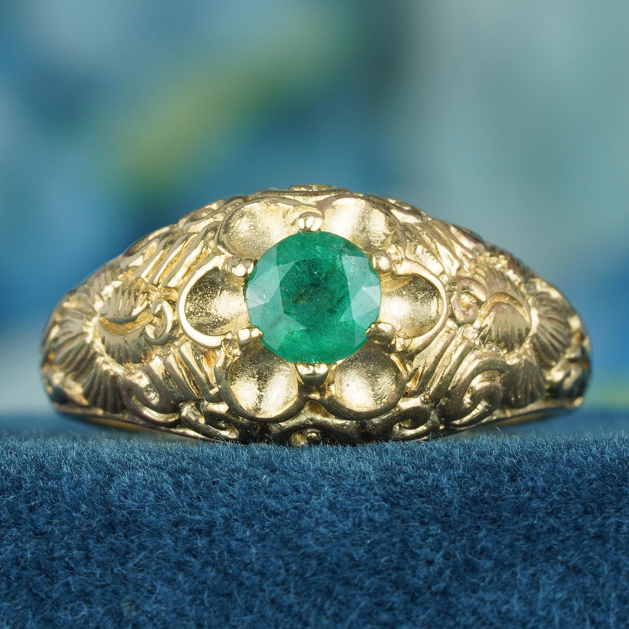 This antique Victorian design large ring showcases a natural, vibrant green, round emerald, creating a striking contrast against the gold setting at the center. The band itself features an ornate floral carved design that further enhances its