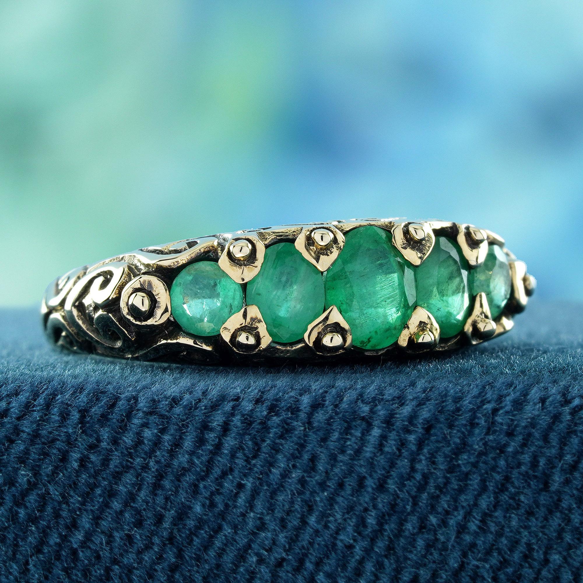 The focal point of this vintage-inspired ring lies in its array of five gemstones. Captivating emeralds add a touch of sparkle and grace to the ensemble. Crafted in a yellow gold prong setting, the vibrant green color of the gemstones forms a