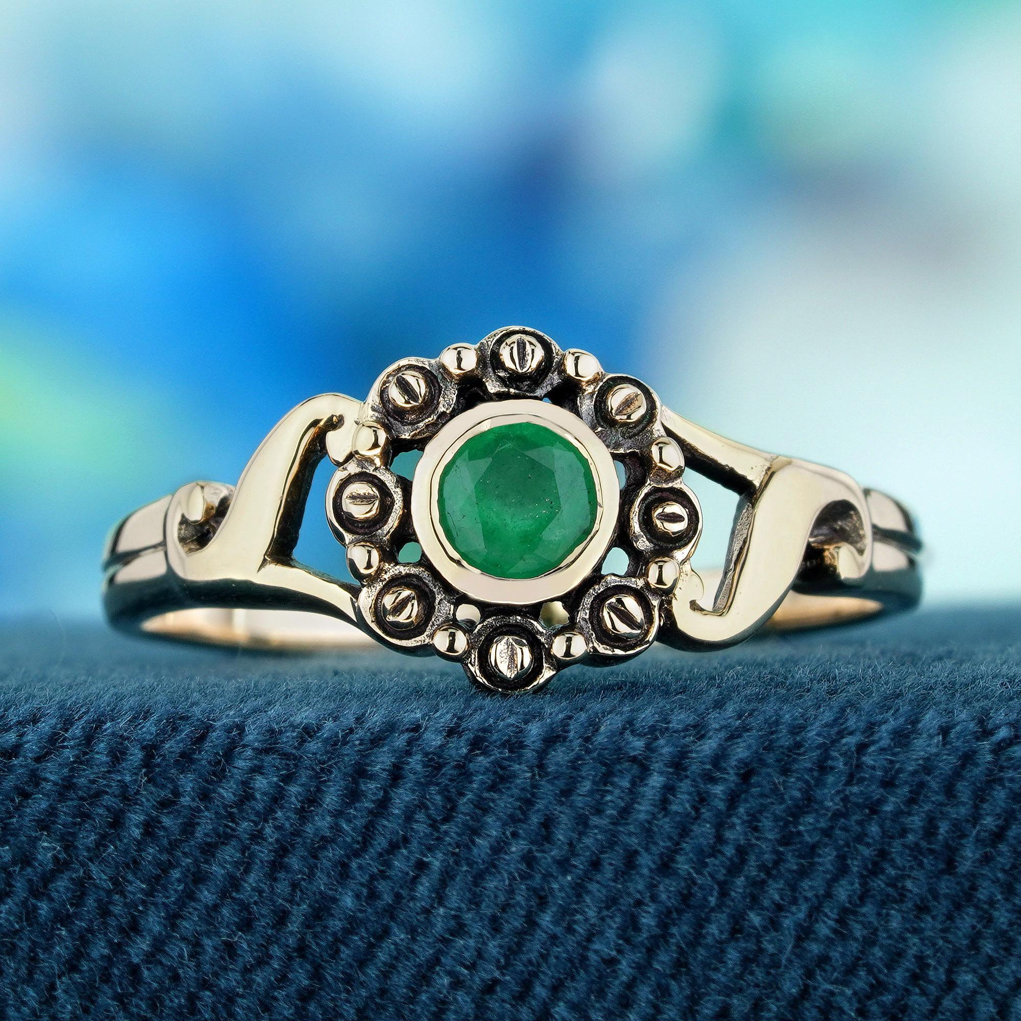 Enhance your hand with a delicate and distinctive flair with this vintage-style ring in yellow gold. Featuring a round emerald at its center, radiating a rich green hue, this piece exudes sophistication. The band, adorned with decorative floral