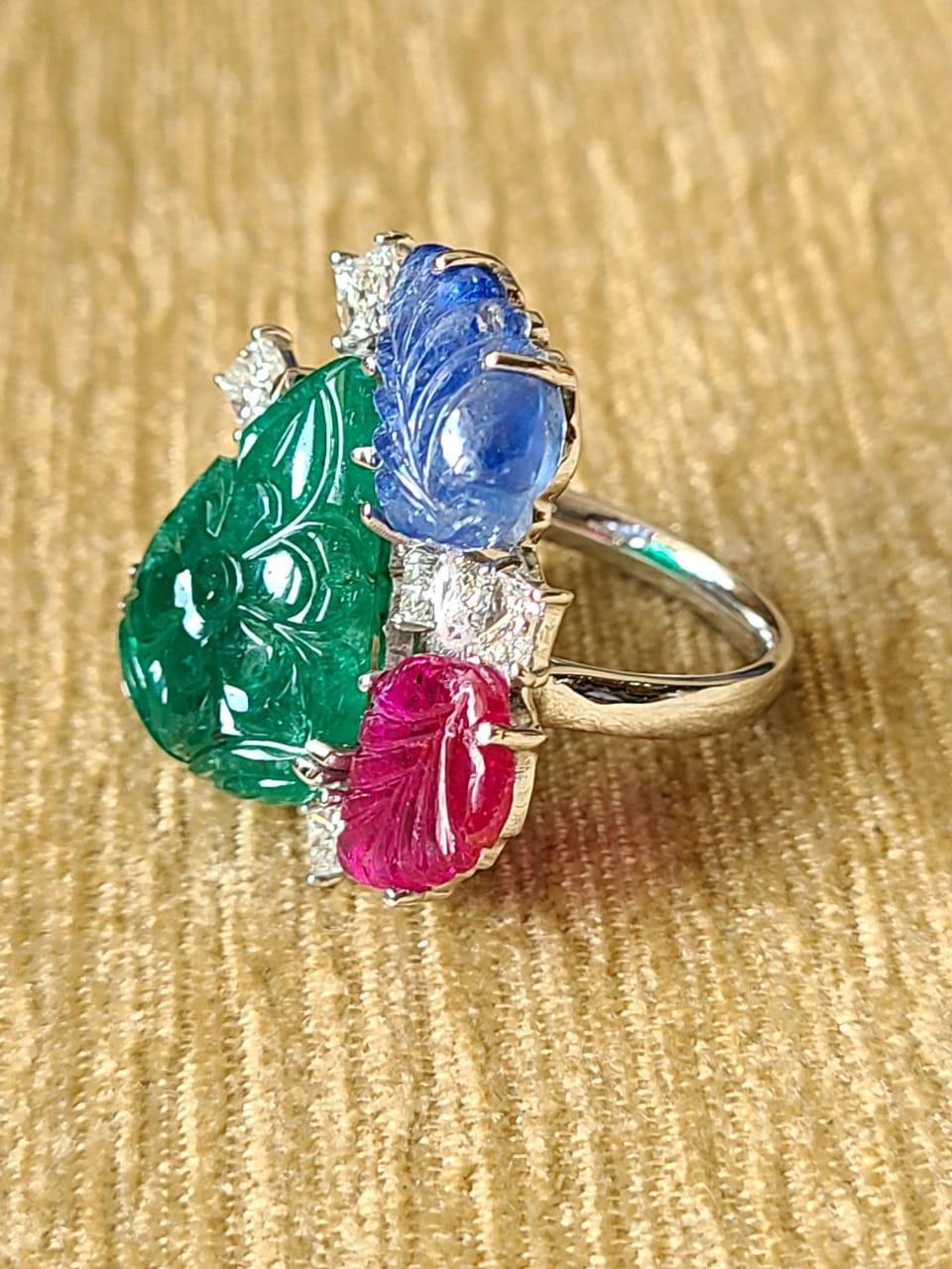 A very wearable and one of a kind, natural carved Emerald, Blue Sapphire & Ruby Cocktail Ring set in 18K Gold & Diamonds. The weight of the Emerald is 11.03 carats and of Zambian origin. The weight of the Blue Sapphire is 5.54 carats and is of