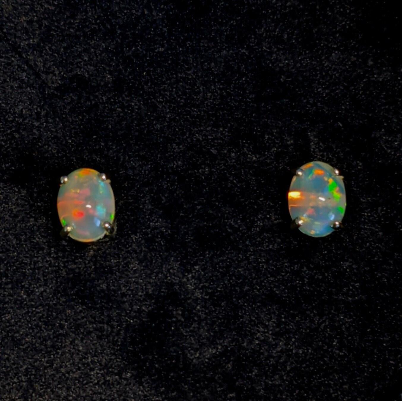 Ces magnifiques boucles d'oreilles en or massif 14 carats sont ornées de pierres centrales ovales en opale éthiopien de 8 x 6 mm, créant un look amusant et ardent. Un design de boucle d'oreille solitaire parfait pour des fiançailles ou un