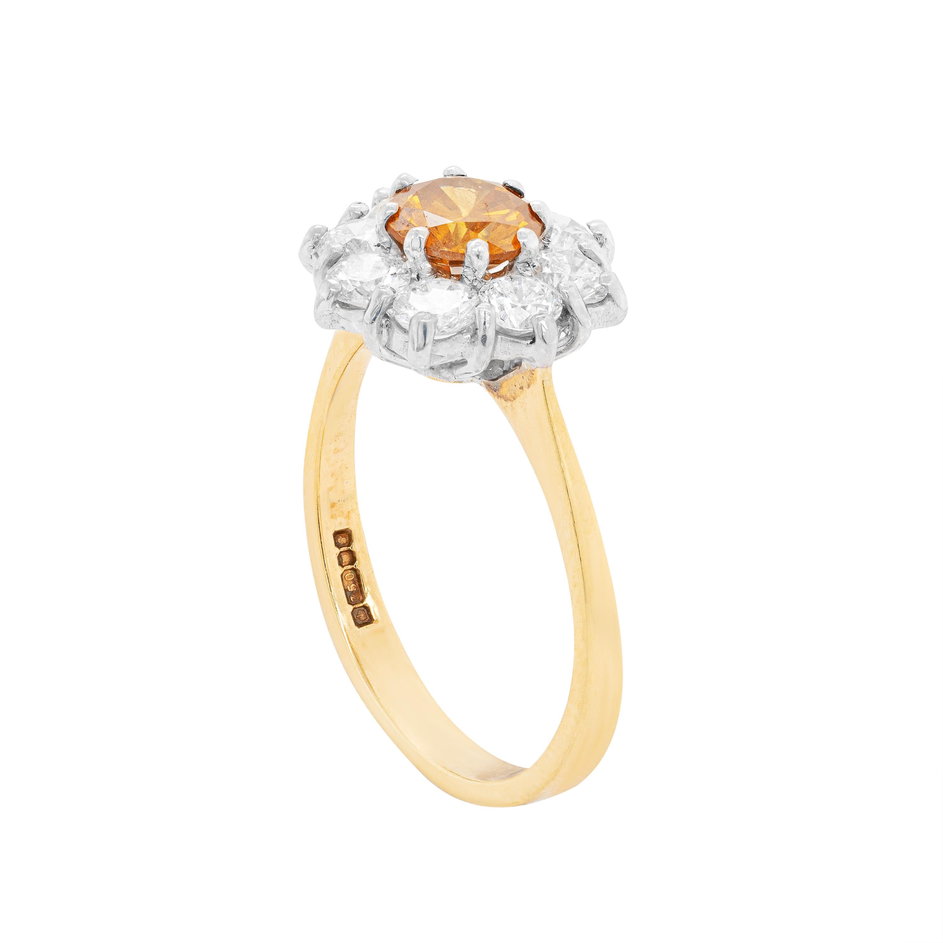 This timeless cluster engagement ring features a GIA certified 0.83ct natural fancy deep orange-yellow diamond centre, mounted in an 8 claw, open back setting. The vibrant stone is perfectly surrounded by eight fine quality round brilliant cut
