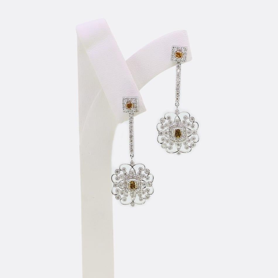 This is a stunning pair of 18ct white gold fancy diamond earrings. Each earring has been set with 43 round brilliant cut diamonds and 2 natural fancy orangey/brown coloured diamonds. The earrings have been crafted in 18ct white gold in a halo