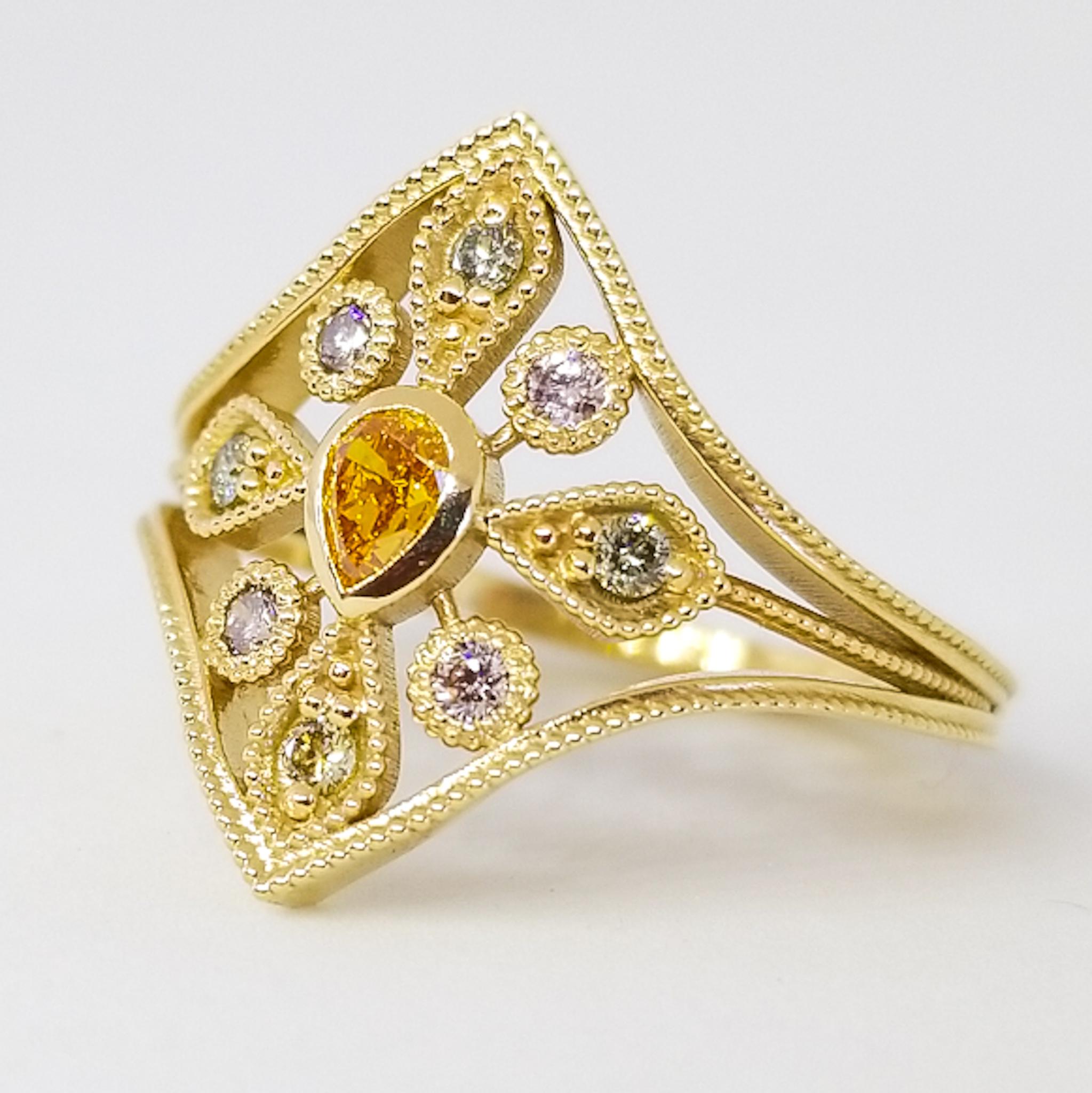 Natural Fancy Color Diamond Cluster Ring in 18 Karat Yellow Gold. This one of a kind Ring features a Suite of nine, Natural Fancy Color Diamonds. The center stone is a bezel set, Pear shape Natural Vivid Orange Diamond. Set around the center stone