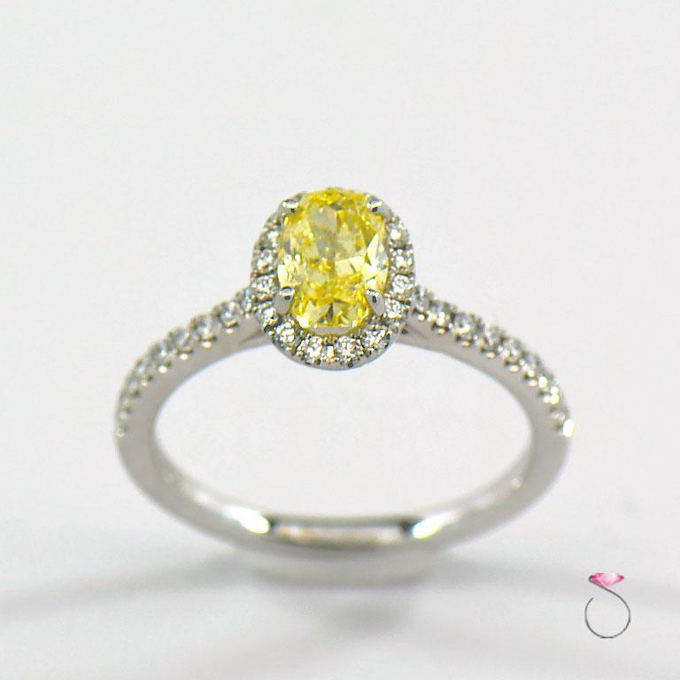 Stunning natural fancy intense yellow diamond ring with white diamond halo. This magnificent ring features a 1.01 carat oval shape natural fancy intense yellow Diamond in the center surrounded by a white diamond halo. The 1.01 carat center diamond
