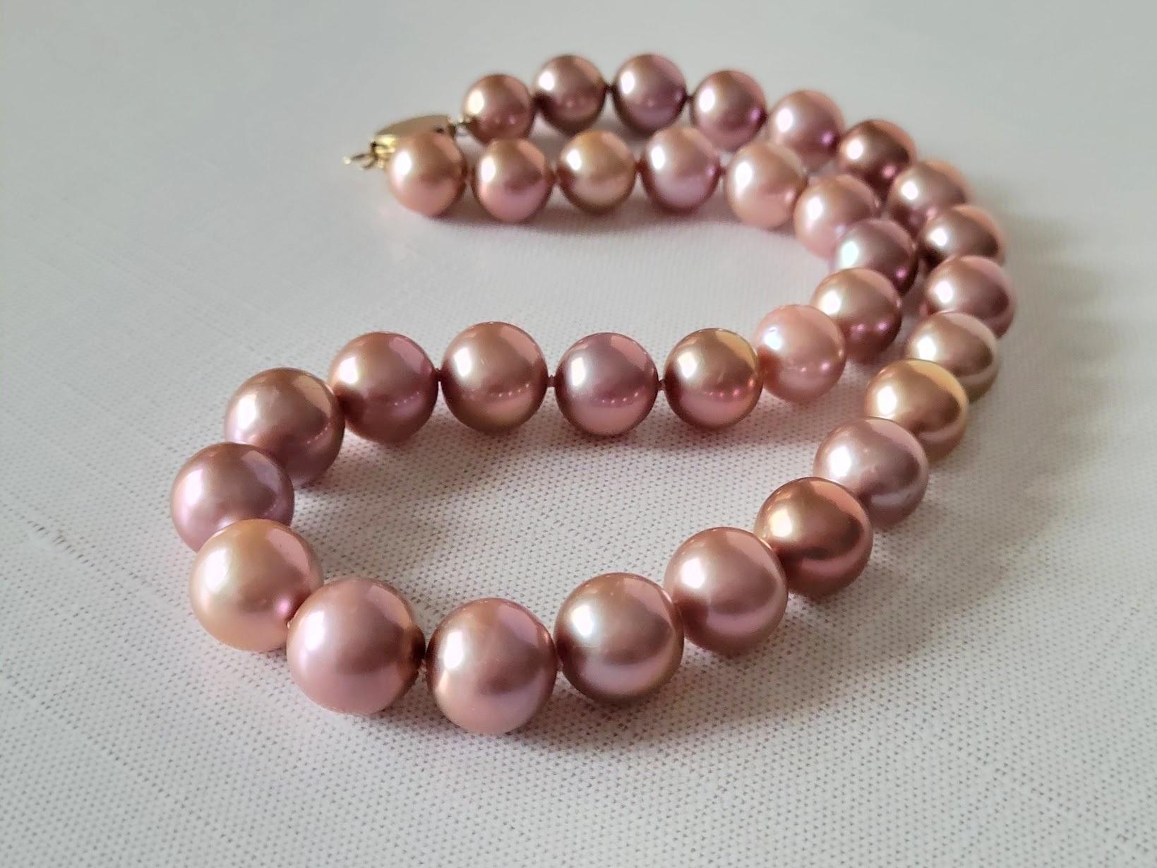 Indulge in the timeless beauty of this exquisite dark pink metallic shade Edison pearl necklace. Measuring 17.5 inches (44.5 cm), this elegant piece features pearls ranging from 11.5 to 13.5 mm, displaying a harmonious gradient in shape and color.