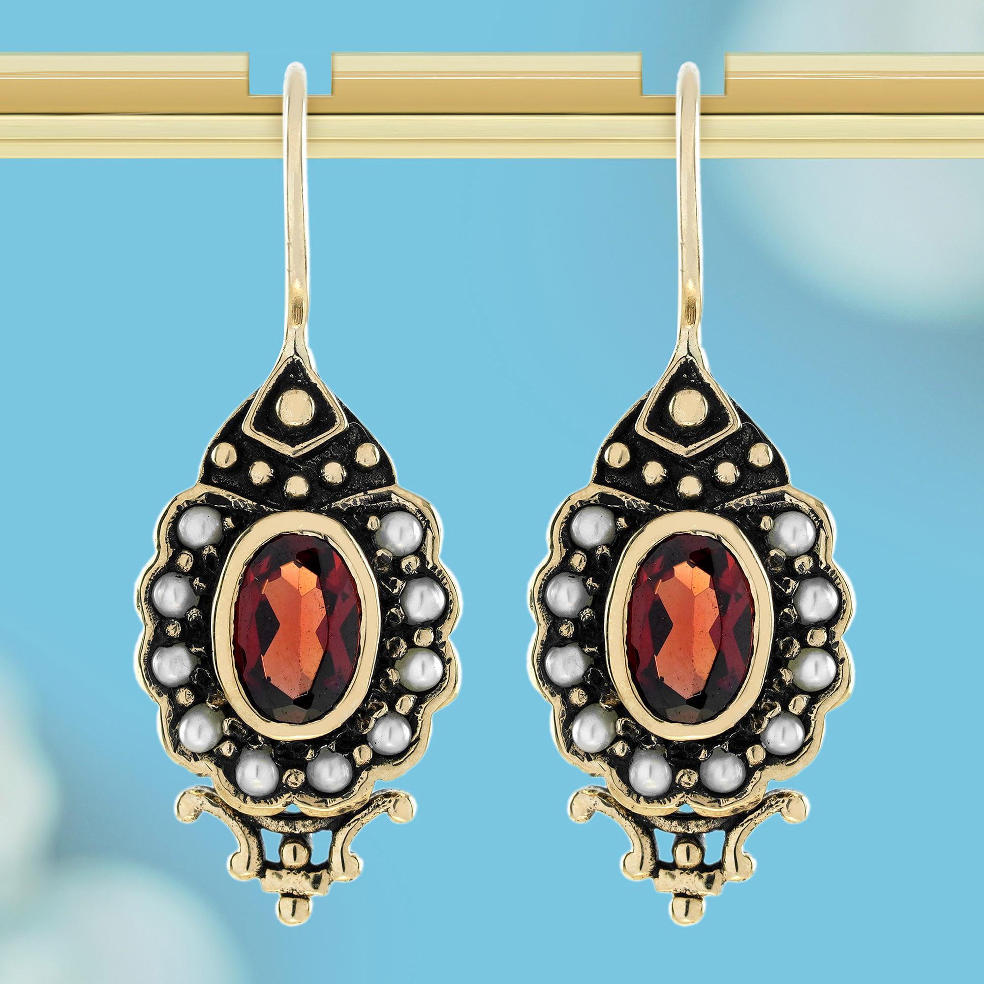 These earrings epitomize grandeur with intricate patterns reminiscent of flowers and nature. Each earring forms a dazzling cluster, showcasing a red garnet gemstone at its center, encircled by a ring of white pearls. Set within a beautiful,