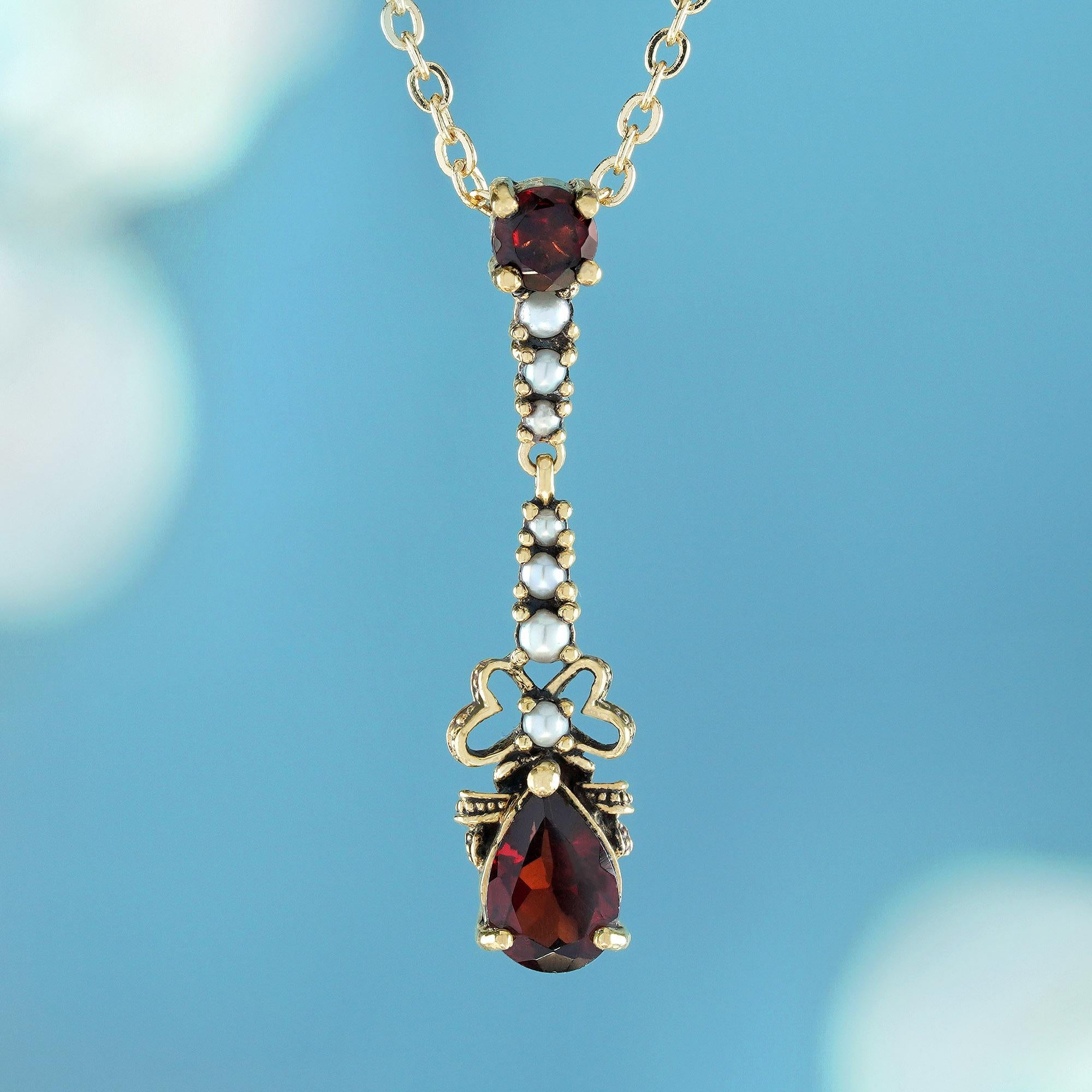 Confectionné dans un style vintage en or jaune massif, ce pendentif est orné de deux grenats en serti clos en son centre - un petit grenat rond en haut et un grand grenat en forme de poire en bas. Entre ces pierres précieuses en grenat rouge se