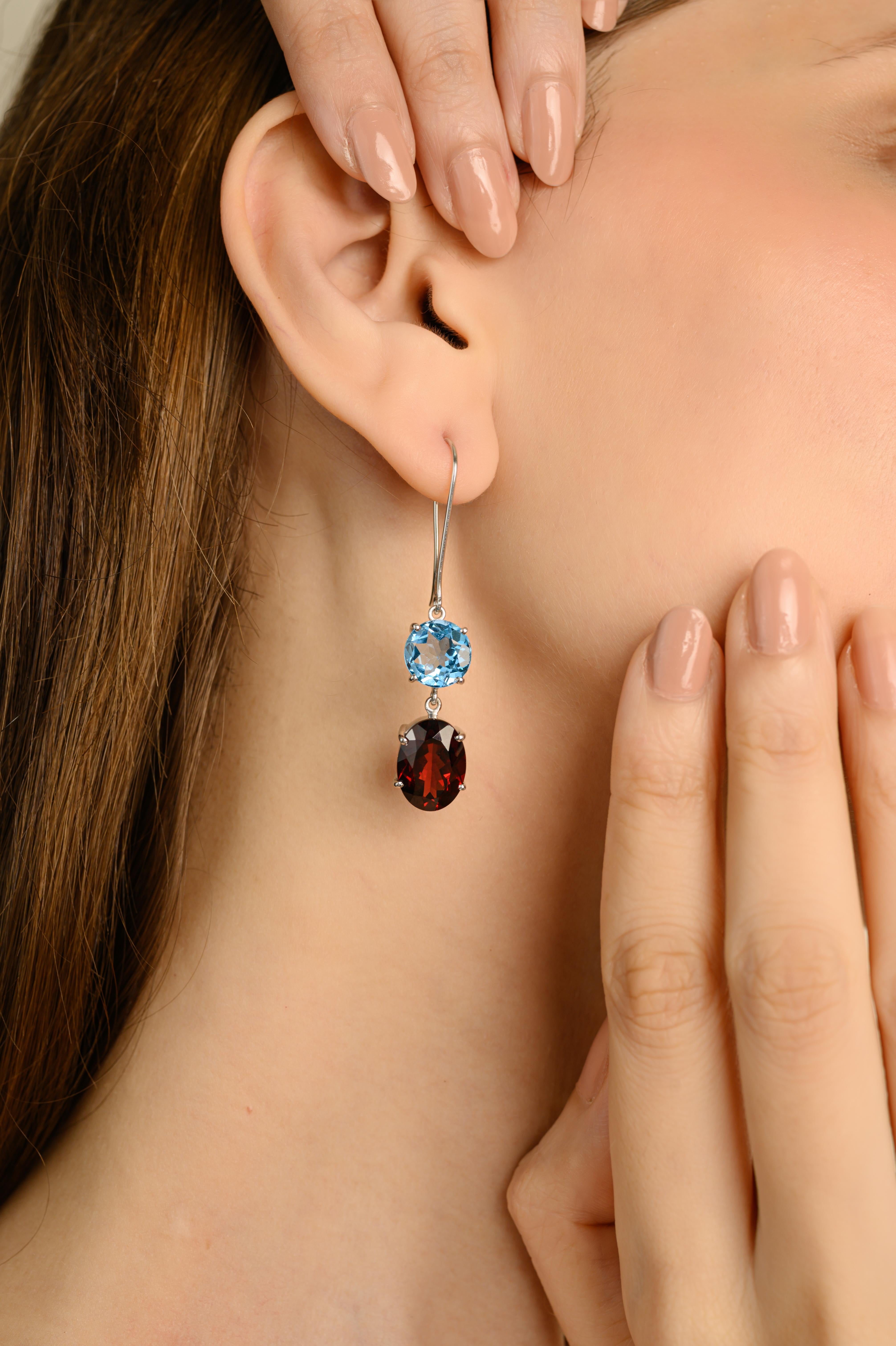 Questi orecchini pendenti in argento con granato naturale e topazio a due pietre sono realizzati a mano e presentano una vivace combinazione di gemme naturali in argento sterling 925. Un luminoso topazio blu a taglio rotondo si trova sopra un ricco