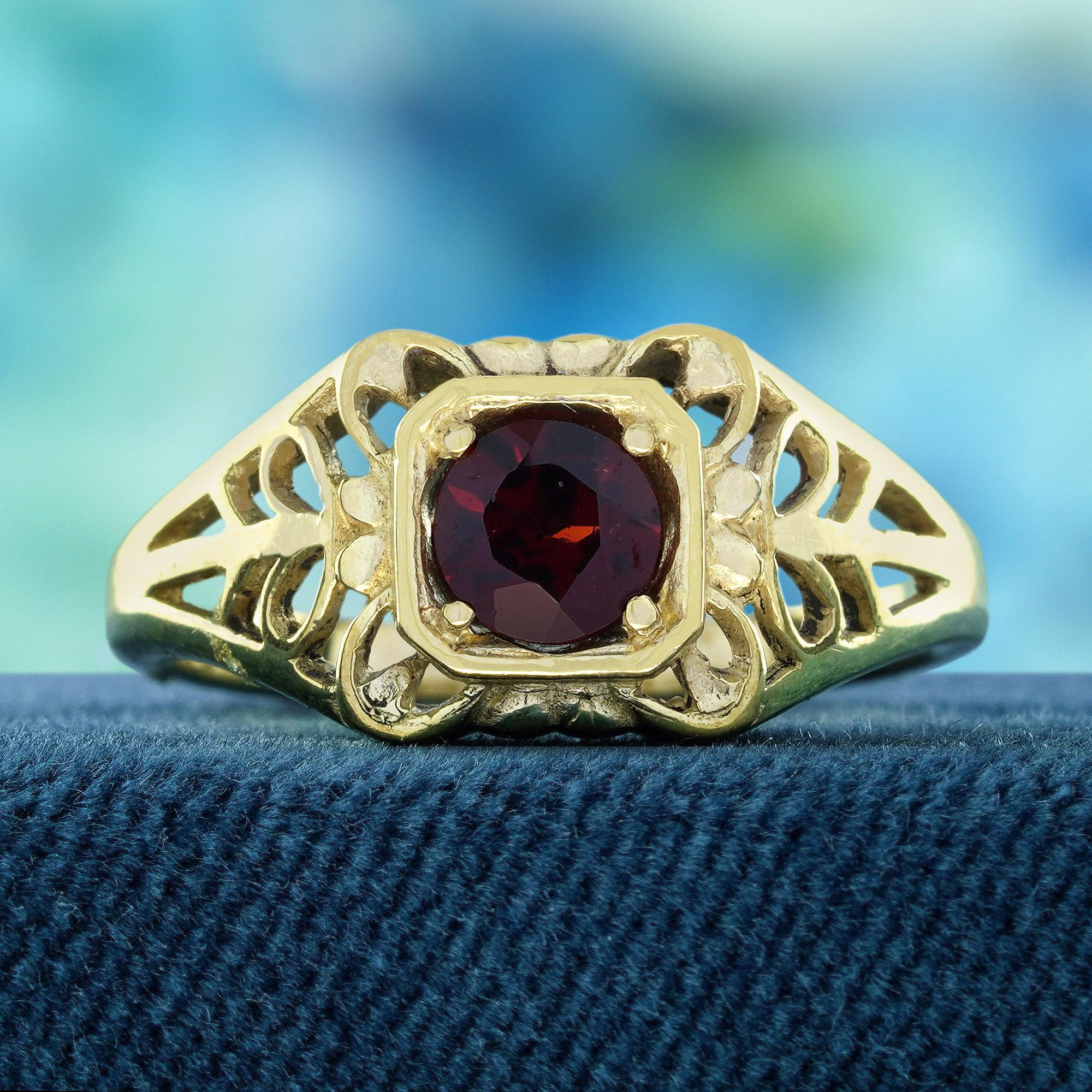 Cette étonnante bague de style vintage en or jaune 9 carats, ornée d'un grenat naturel ajouré, présente un magnifique grenat naturel rond, solidement serti en son cœur, rayonnant d'élégance et de charme. Mais attendez ! Les épaules ajourées, ornées
