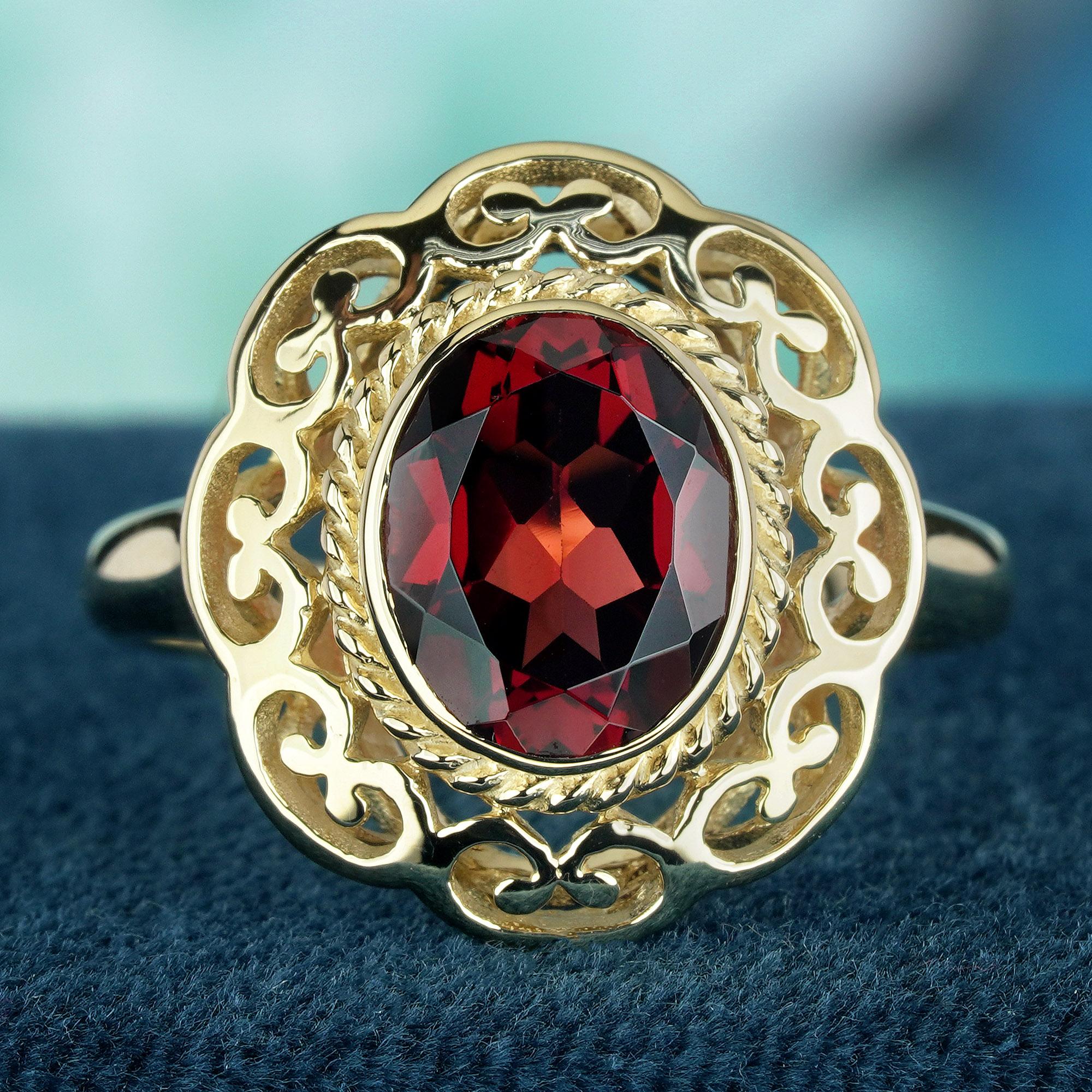 Adorned with a fiery oval red garnet gemstone and set in intricate open-work gold setting, this ring stands as a masterpiece of craftsmanship. The delicate swirling carved ring face speaks volumes about artistry and meticulous attention to detail.