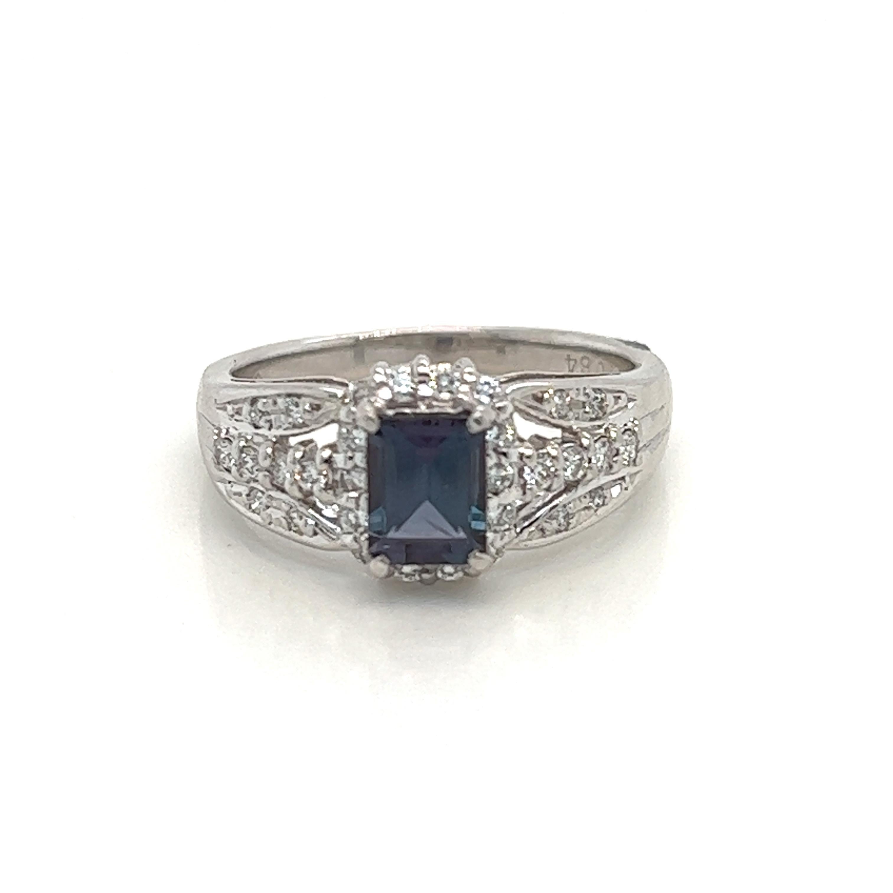 This is a gorgeous natural AAA quality emerald cut Alexandrite surrounded by dainty diamonds that is set in a vintage platinum setting. This ring features a natural 0.84 carat emerald cut alexandrite that is certified by the Gemological Institute of