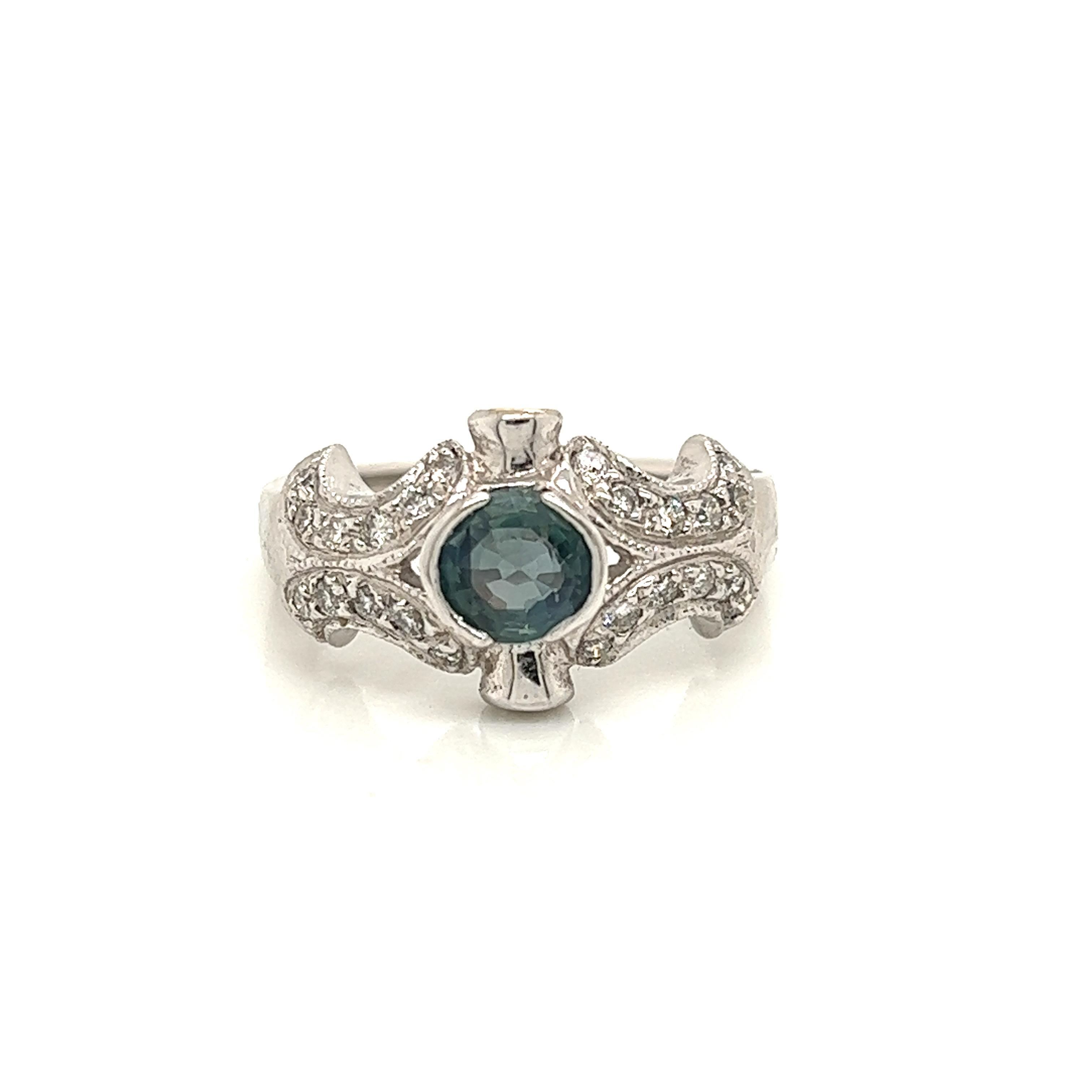 This is a gorgeous natural AAA quality oval Alexandrite surrounded by dainty diamonds that is set in a vintage white gold setting. This ring features a natural 1.11 carat oval alexandrite that is certified by the Gemological Institute of America