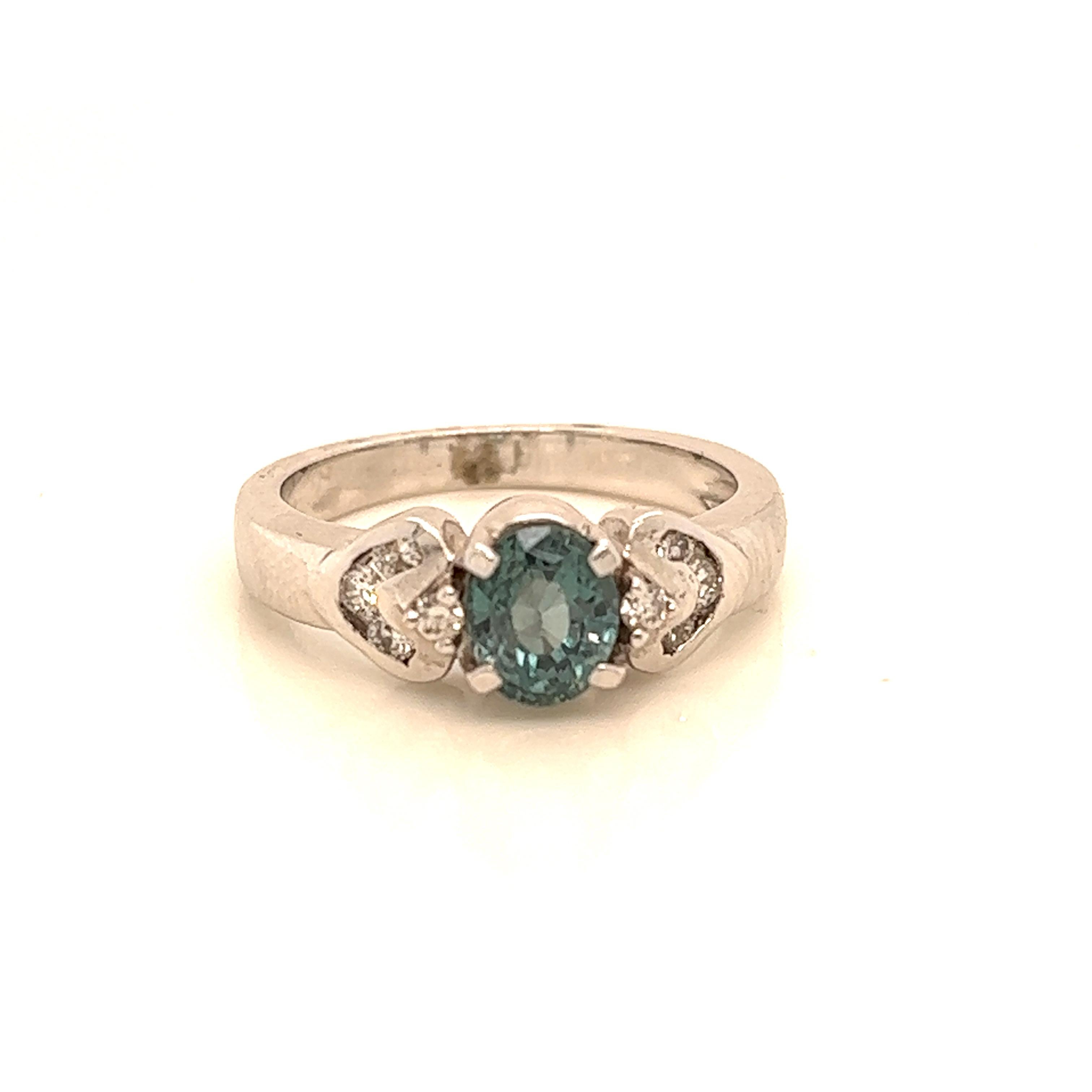 This is a gorgeous natural AAA quality oval  Alexandrite surrounded by dainty diamonds that is set in a vintage white gold setting. This ring features a natural 1.26 carat oval alexandrite that is certified by the Gemological Institute of America