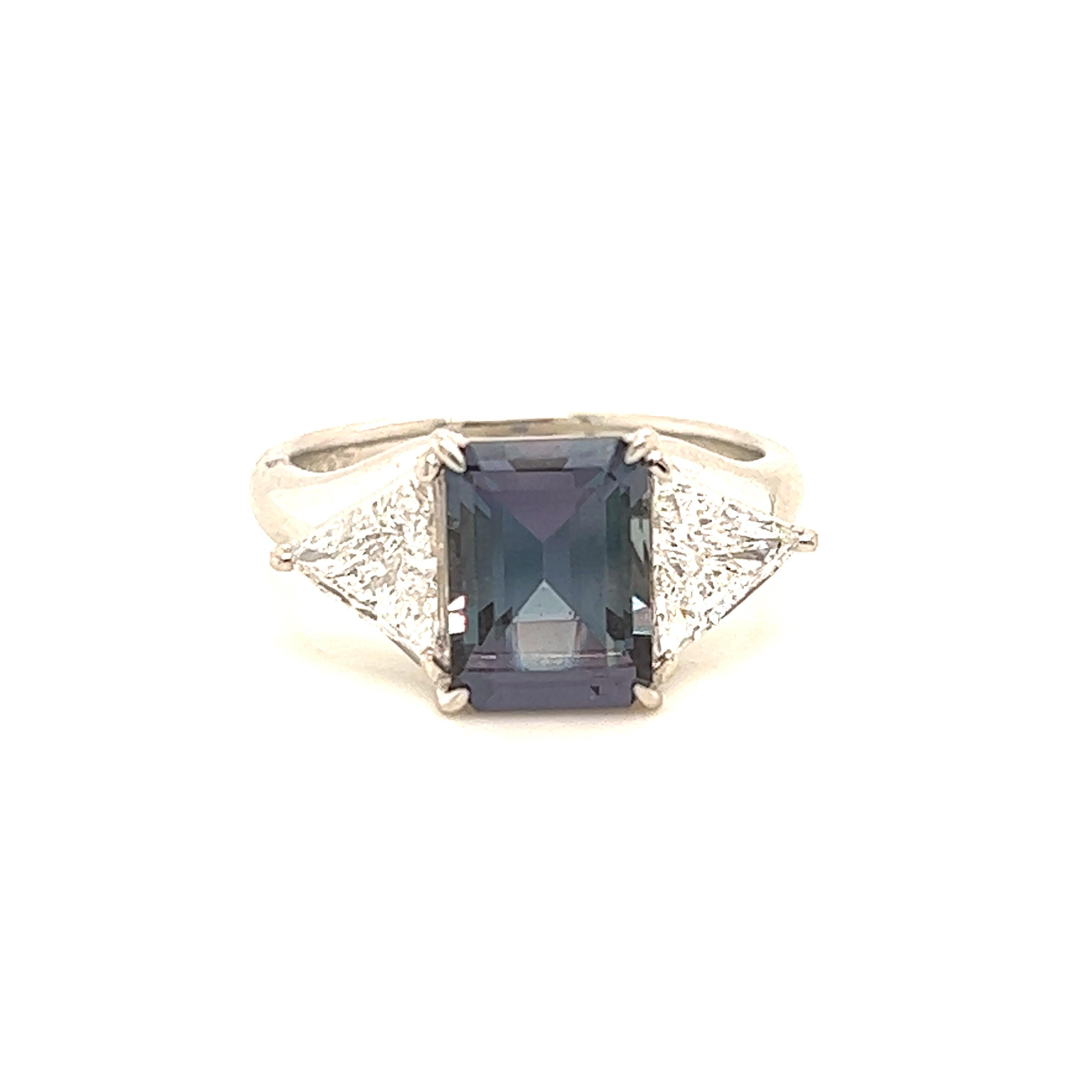 This is a gorgeous natural AAA quality emerald Alexandrite surrounded by dainty diamonds that is set in a vintage platinum setting. This ring features a natural 2.62 carat emerald alexandrite that is certified by the Gemological Institute of America