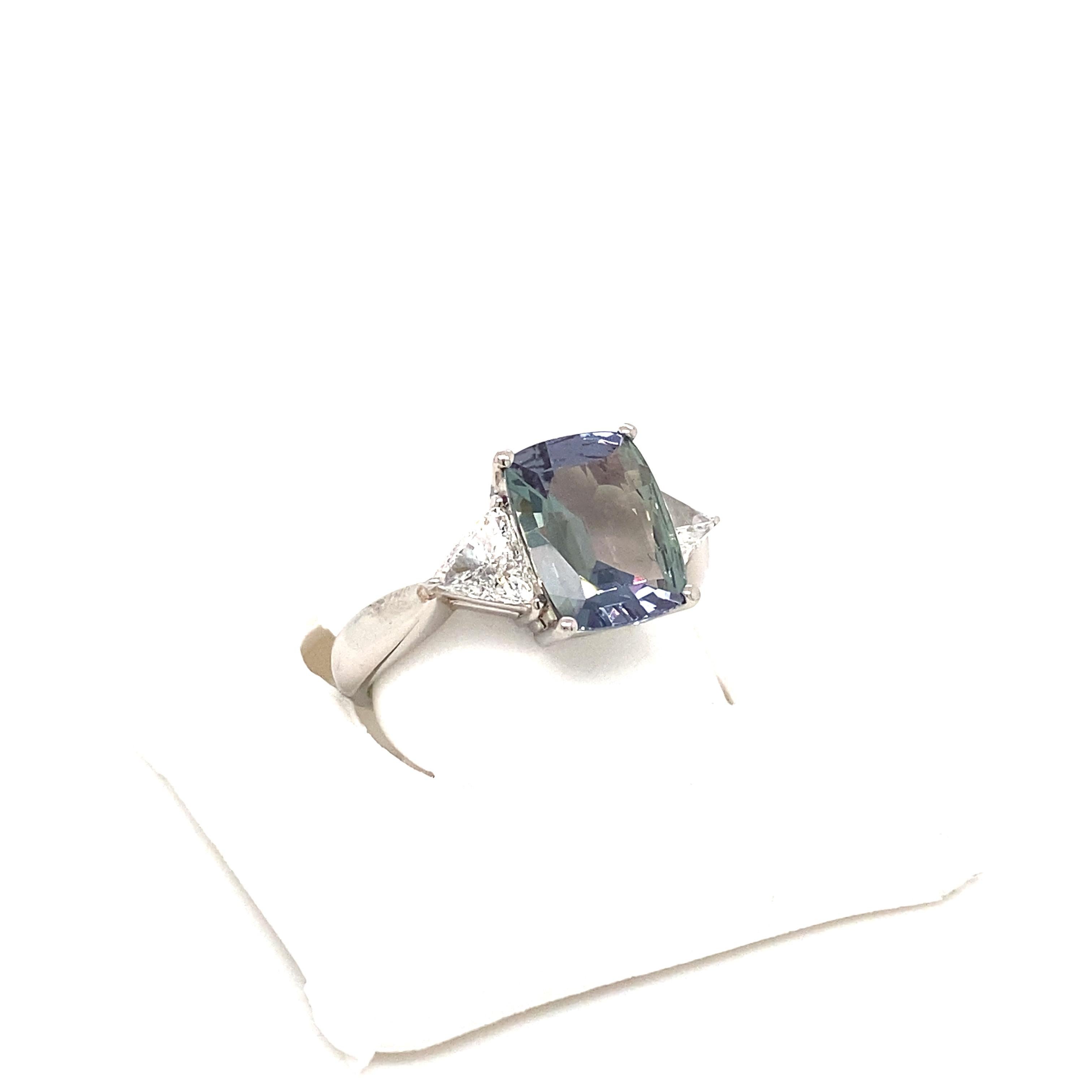This is a gorgeous natural AAA quality cushion Alexandrite surrounded by dainty diamonds that is set in a vintage platinum setting. This ring features a natural 3.12 carat cushion brazilian alexandrite that is certified by the Gemological Institute