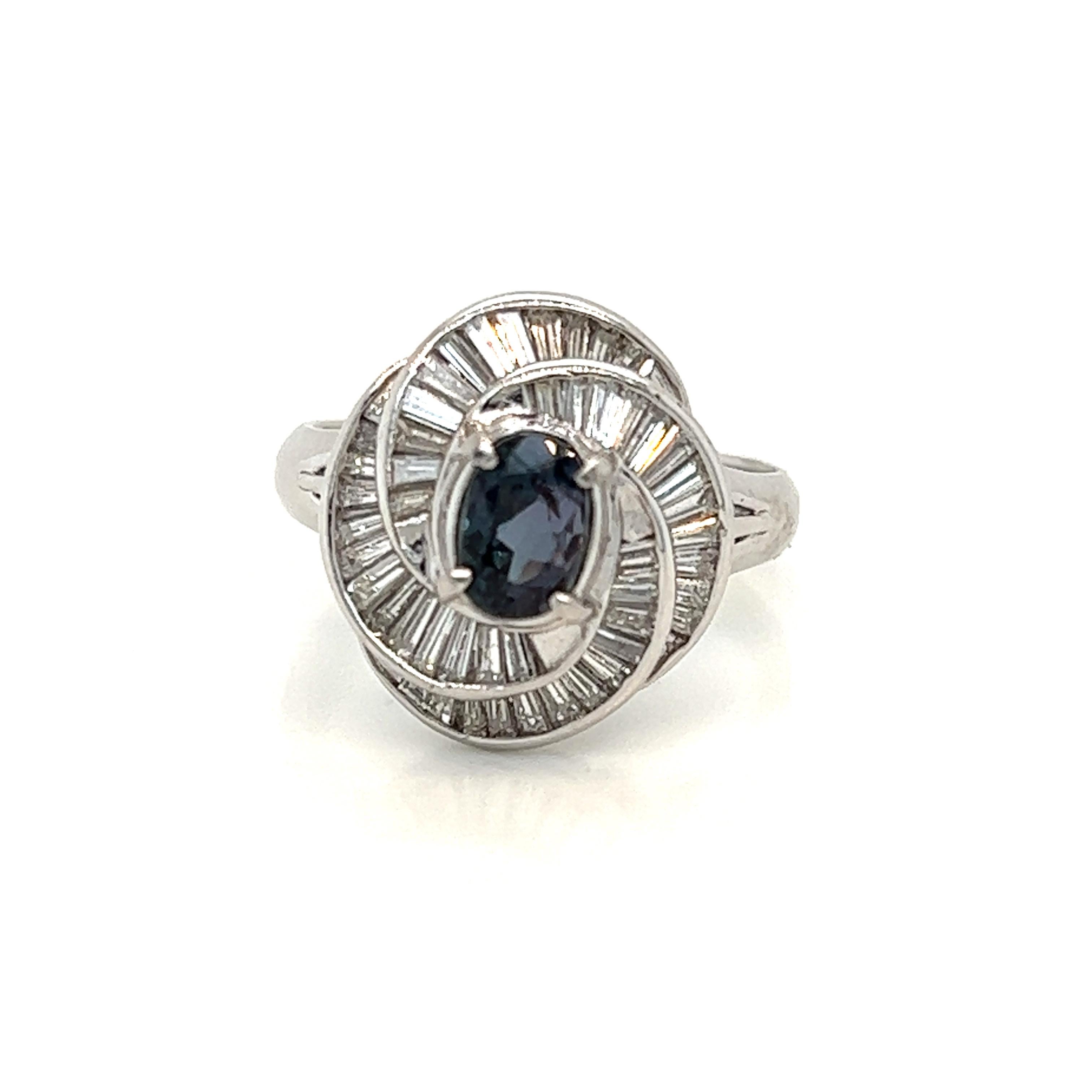 This is a gorgeous natural AAA quality oval Alexandrite surrounded by dainty diamonds that is set in a cocktail platinum setting. This ring features a natural 1.26 carat oval alexandrite that is certified by the Gemological Institute of America
