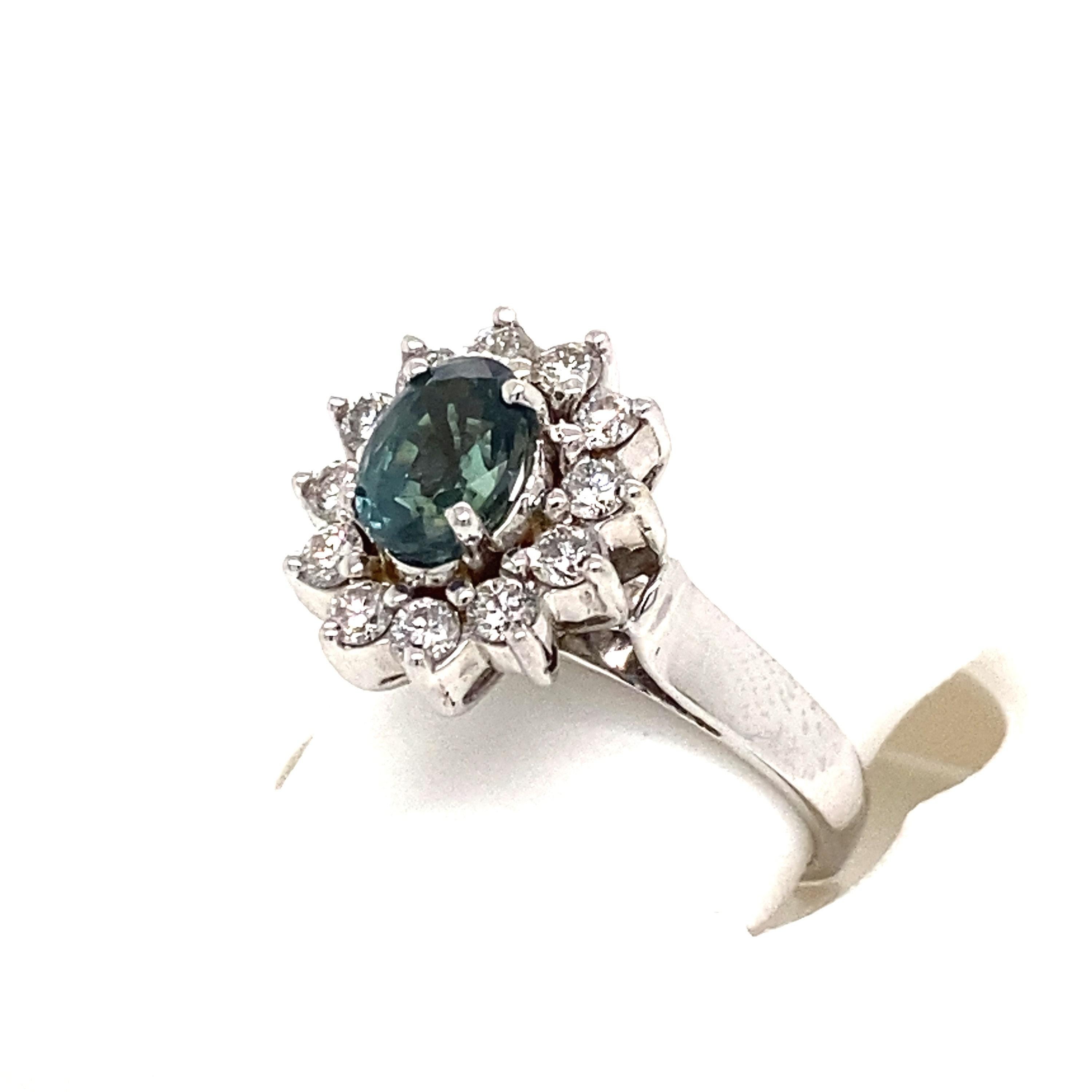 This is a gorgeous natural AAA quality oval Alexandrite surrounded by dainty diamonds that is set in a vintage white gold setting. This ring features a natural 1.25 carat oval alexandrite that is certified by the Gemological Institute of America