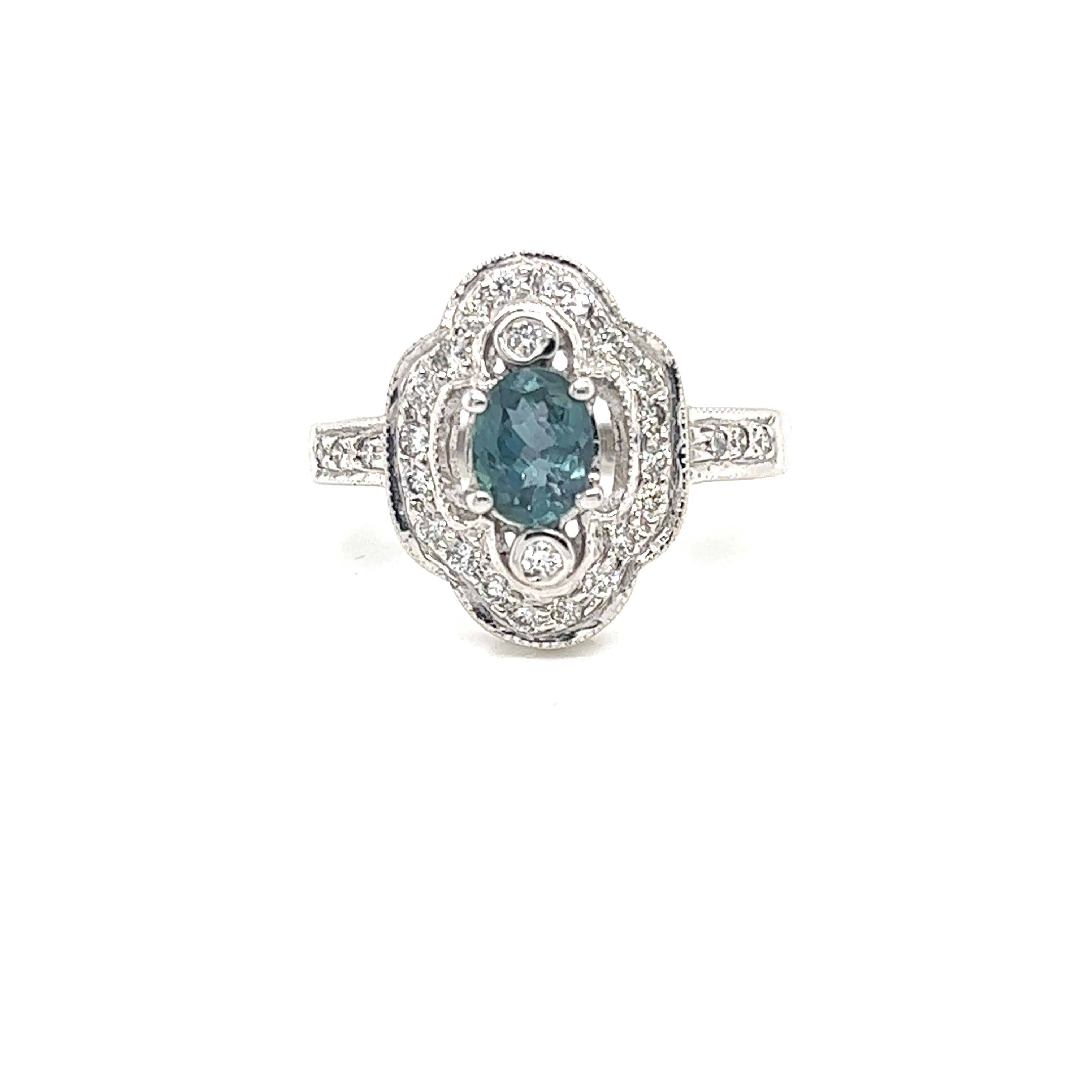 This is a gorgeous natural AAA quality oval Alexandrite surrounded by dainty diamonds that are set in a vintage white gold setting. This ring features a natural 0.75 carat oval alexandrite that is certified by the Gemological Institute of America