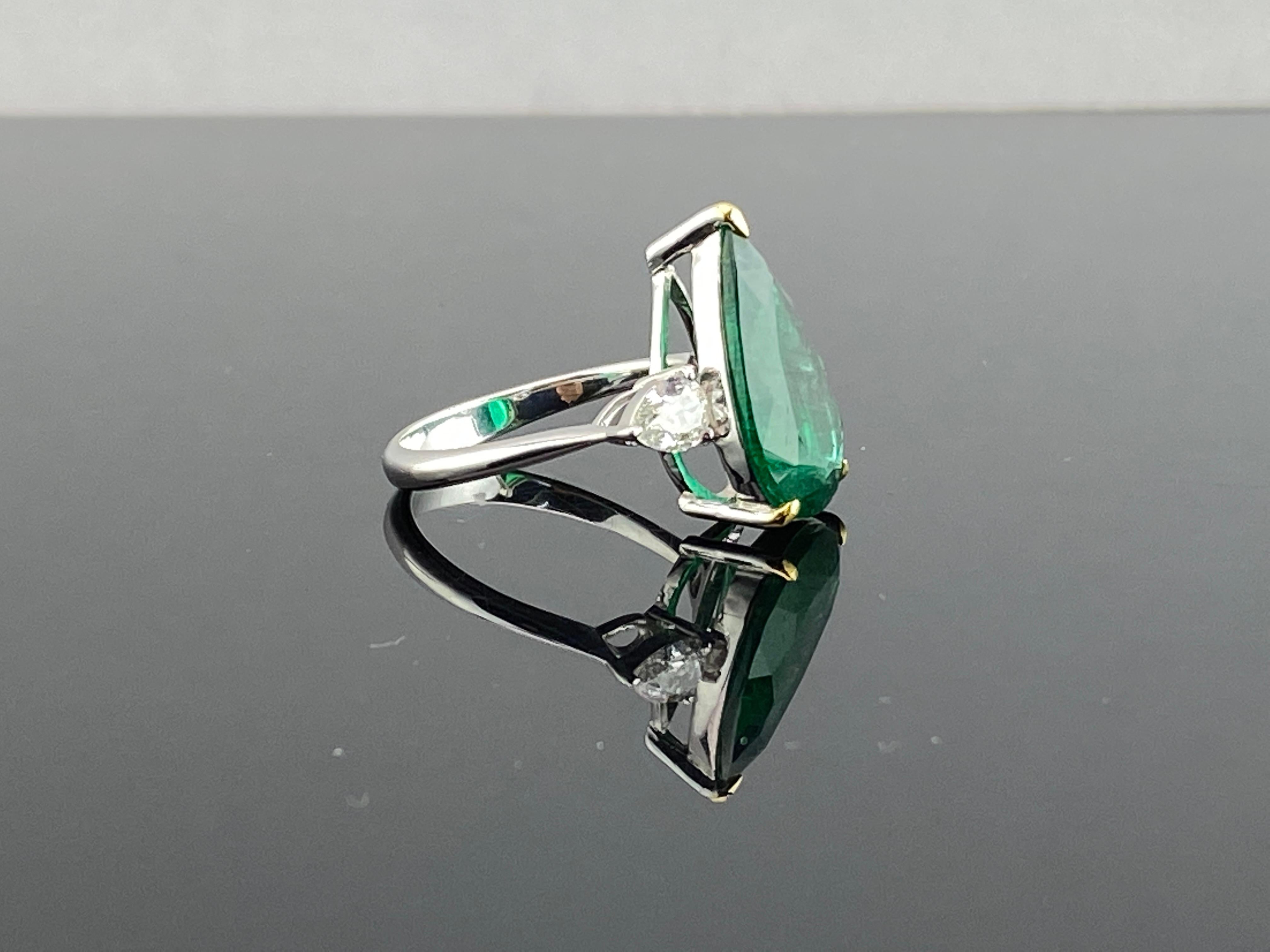 A classic, certified 5.7 carat cushion shaped Zambian Emerald center stone engagement ring, adorned with 0.69 carat pear shape Diamond side stones as side stones. The Emerald is transparent, with a beautiful vivid green color and amazing luster.