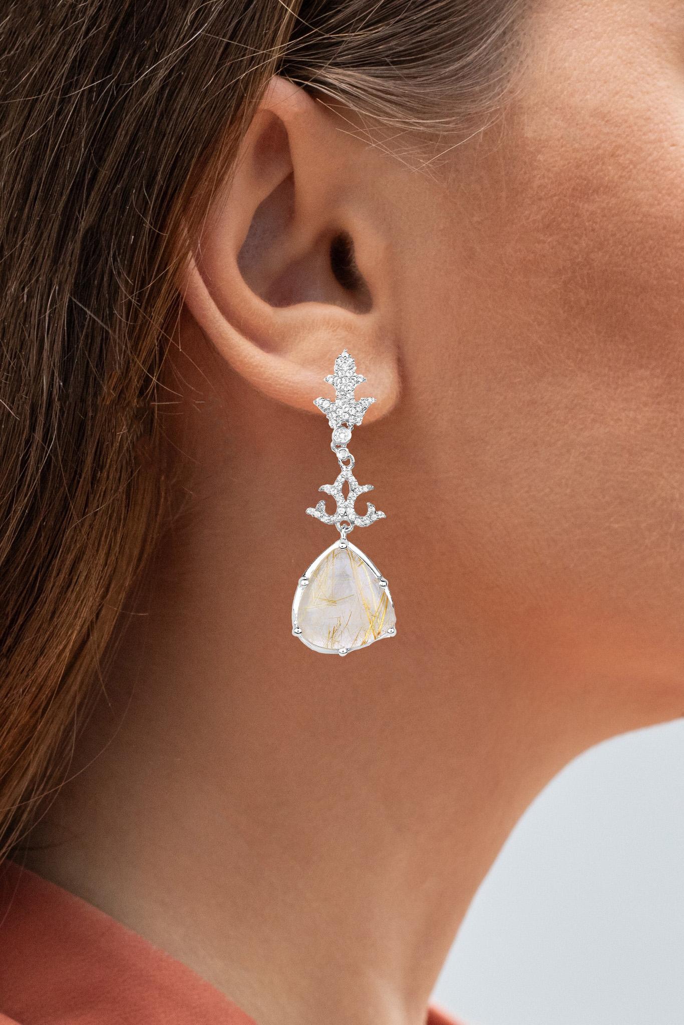 It comes with the appraisal by GIA GG/AJP 
Golden Rutile = 12.50 Carats
Cut: Trillion
White Topaz = 3.50 Carats
Metal: Sterling Silver
Rhodium Plated
Post With Friction Back
Height: 6 mm
Width: 16 mm
Length: 50 mm