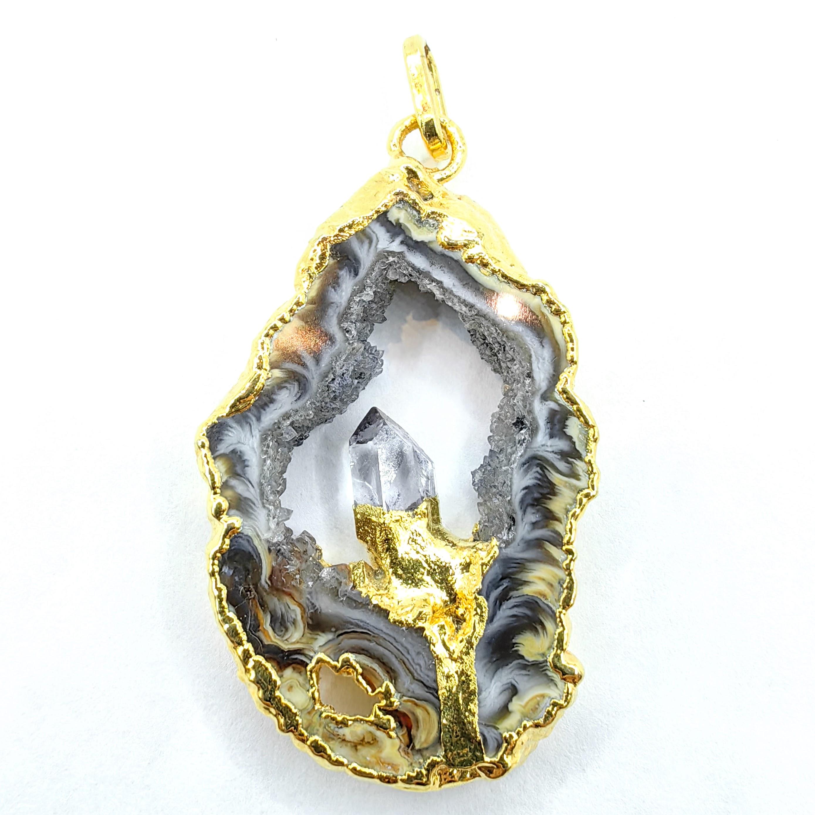 Faites preuve d'audace avec ce collier-pendentif unique en son genre, composé d'agate grise naturelle et de cristal de quartz plaqué or. Cette superbe pièce met en valeur la beauté brute de la Nature. Elle présente une magnifique tranche d'agate