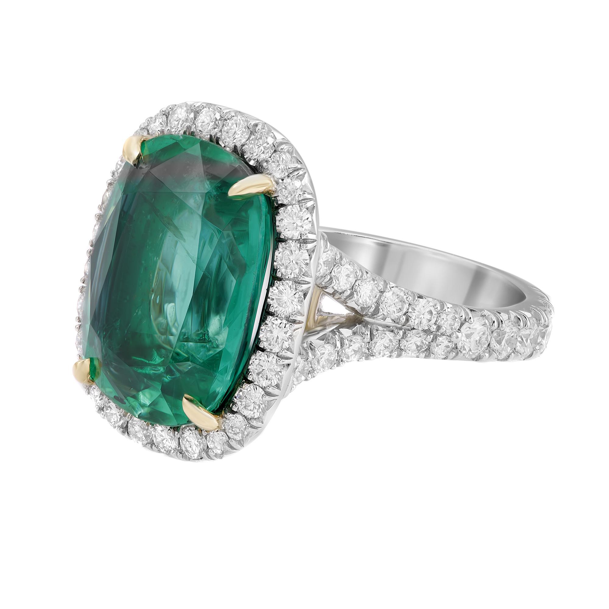Wrap your finger with this extraordinary ring showcasing a prong set GIA certified cushion shaped rich green Zambian Emerald weighing 7.30 carats surrounded by a halo of round brilliant cut diamonds set all through the band. Handcrafted to