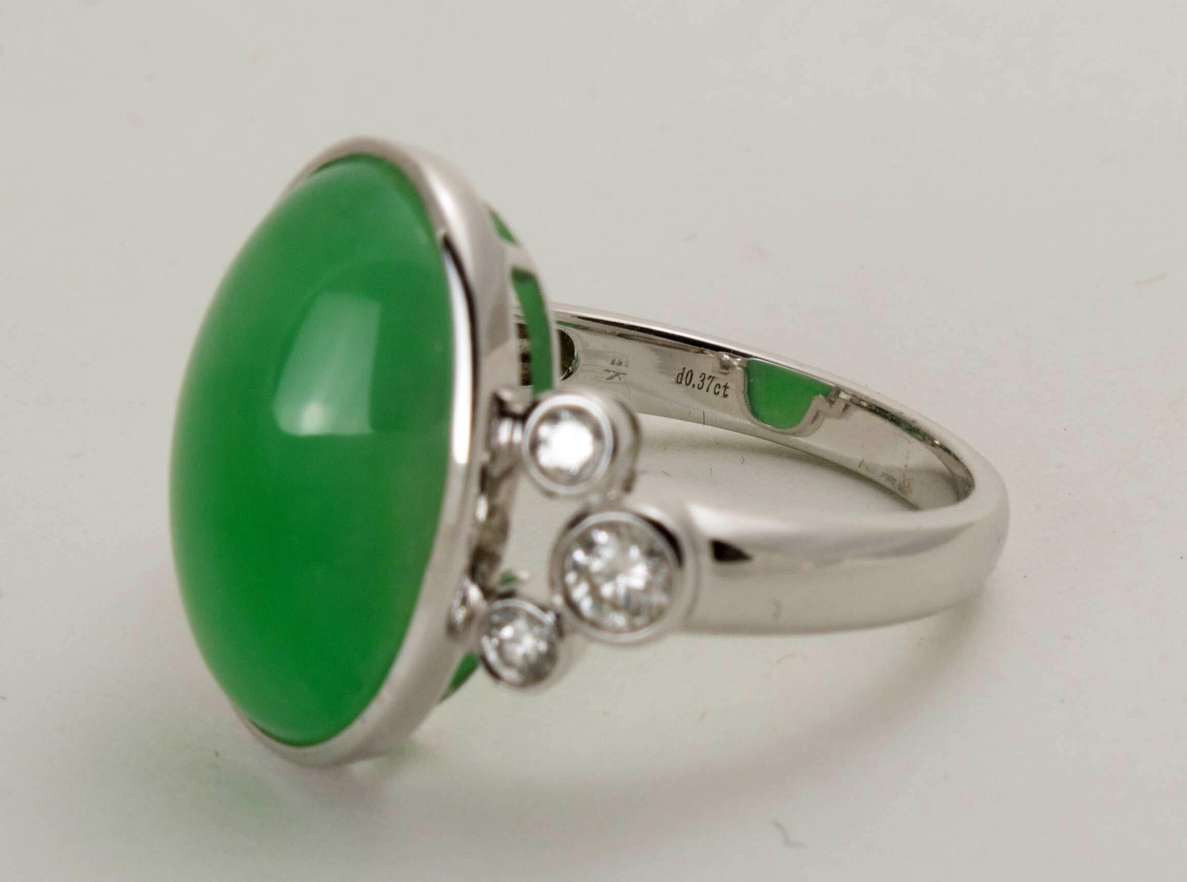 An elegant GIA certified natural green jadeite jade cabochon ring set in 18k white gold with three small round diamonds to either side. Size 7 1/4. 

The natural jadeite cabochon of an enchanting suffused green with an attractive milky translucency.