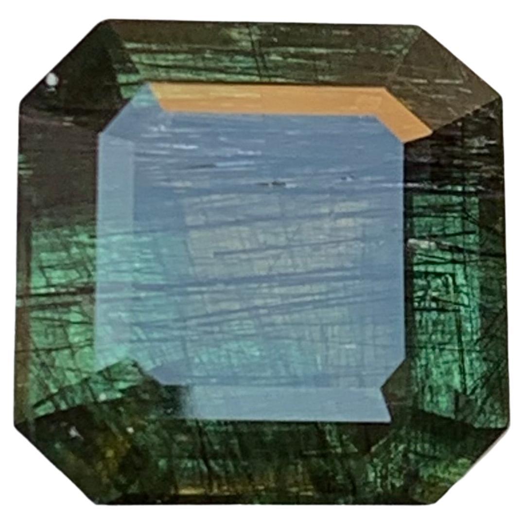 Natural Green Peridot with Dense Ludwigite Needle Inclusions 6.66 Ct Emerald Cut For Sale