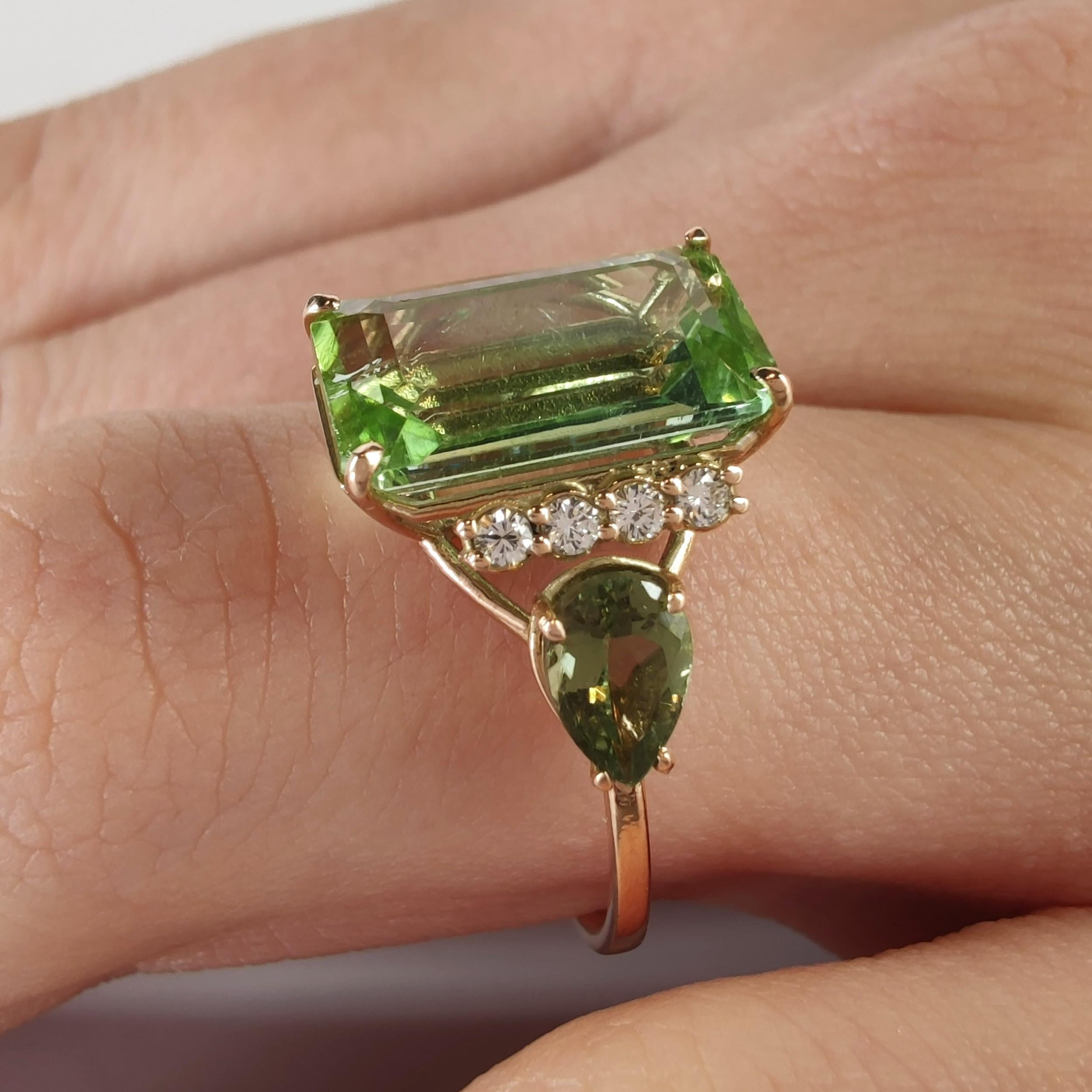 This sculptural cocktail ring blends rich color, symbolic meaning, and fine craftsmanship in one singular piece. Handcrafted in 14K yellow gold, the design centers around a stunning 4.23-carat emerald-cut green tourmaline, admired for its depth of