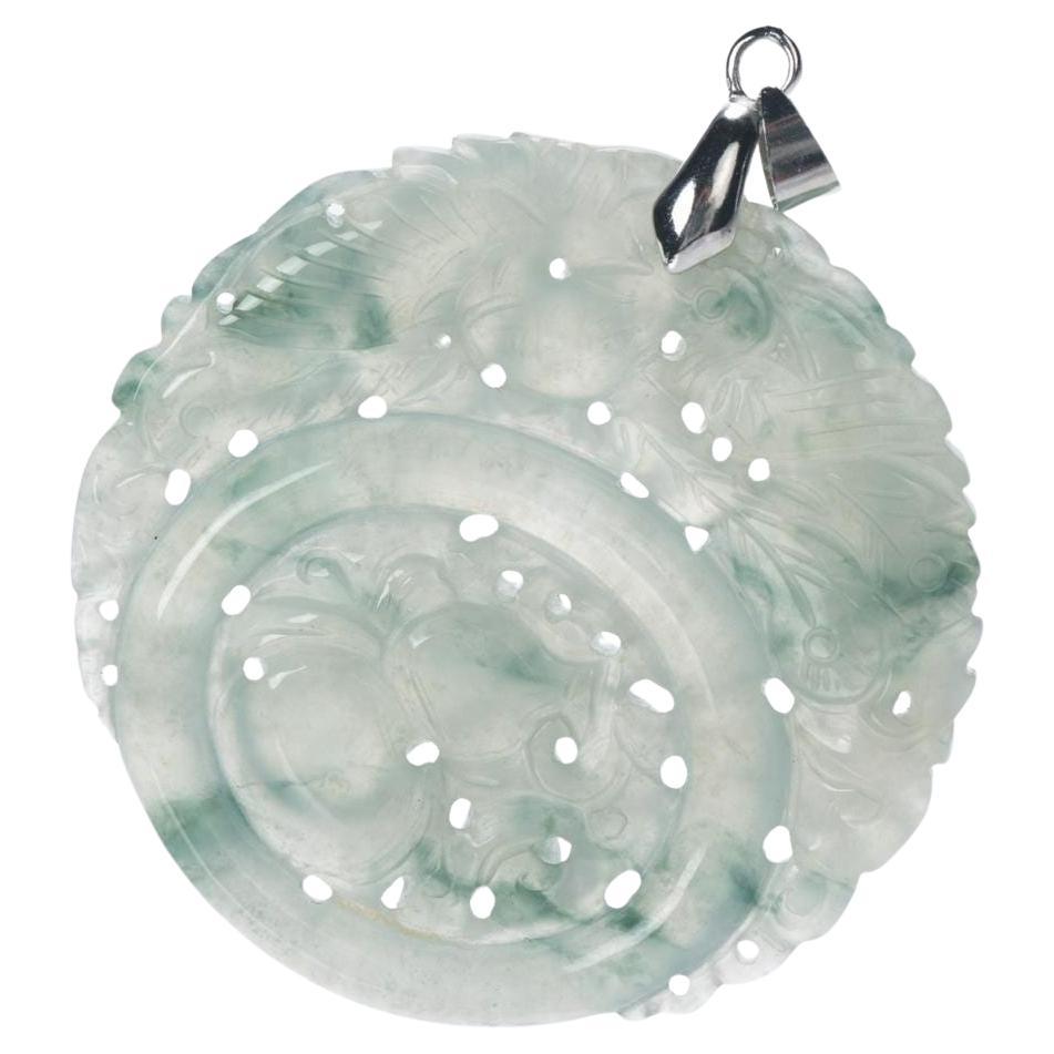 Questo ciondolo di giada naturale mostra un'eccezionale maestria con intagli a mano su due lati e una colorazione traslucida verde ghiaccio e grigio tenue splendidamente bilanciata. Un lato presenta una fenice finemente rappresentata con una zucca