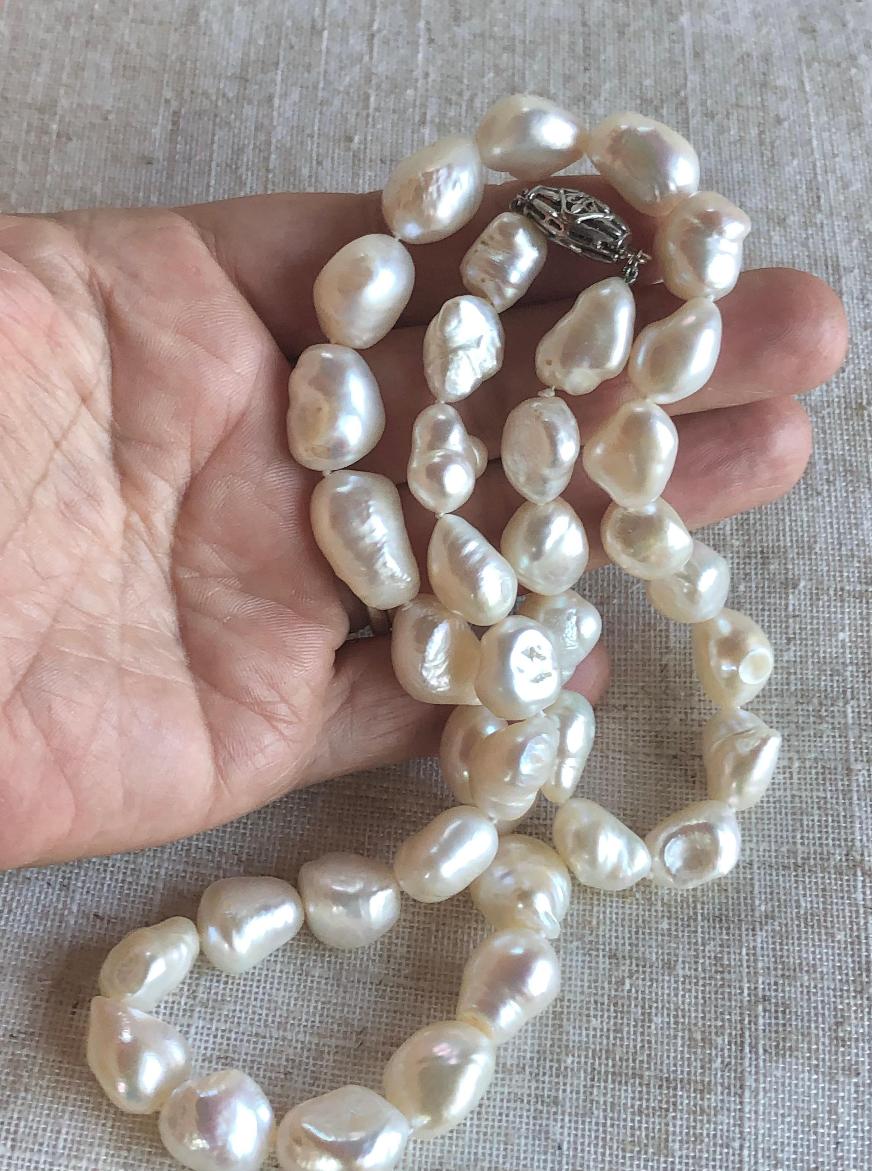 White Natural Big Baroque Pearls. The estate necklace has 38 baroque pearls and each one is completely unique, the necklace is 24 inches long. The largest Pearls are approximately 21mm x 15mm. and the smallest is 10mm x 9mm approx.
Silver clasp.