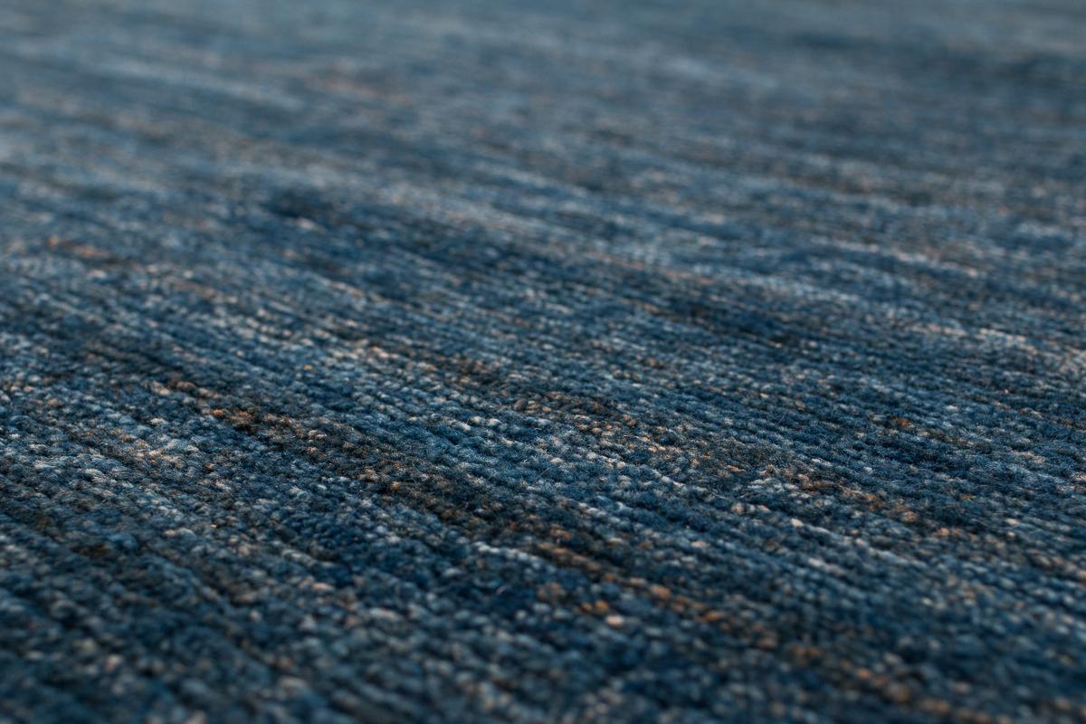 This carpet is woven with a highly textured weave which we have called the Shiva Puri weave. Using the finest Himalayan wool to create a bold, luscious and durable rug. This rug boasts beautiful color variation using all natural indigo dye.