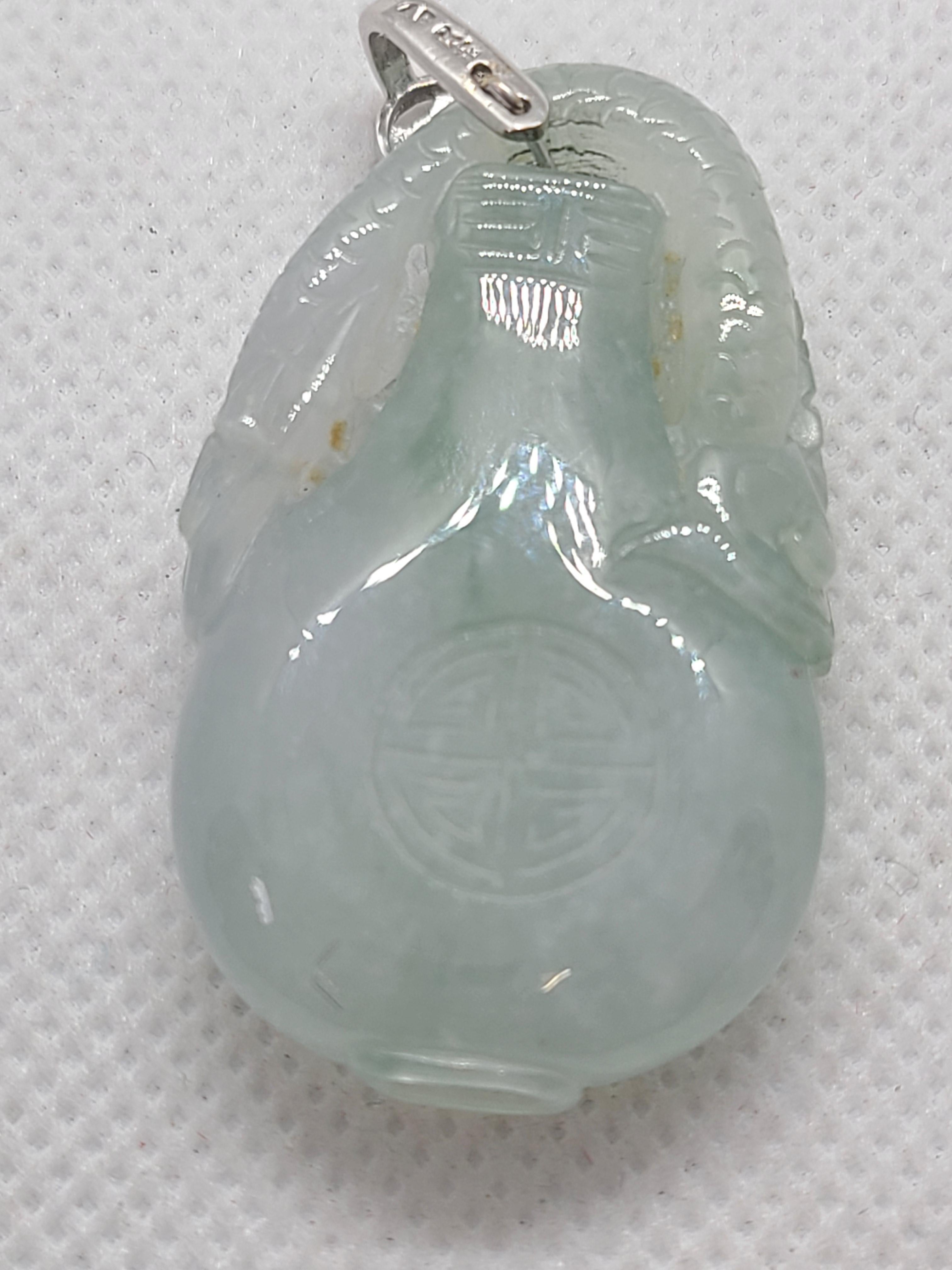 Colgante de jadeíta verde hielo, natural y translúcido, tallado con precisión para representar a un dragón que juega con una pelota mientras se eleva sobre una botella. Este motivo simboliza la paz, la buena fortuna y la salud. Con unas medidas