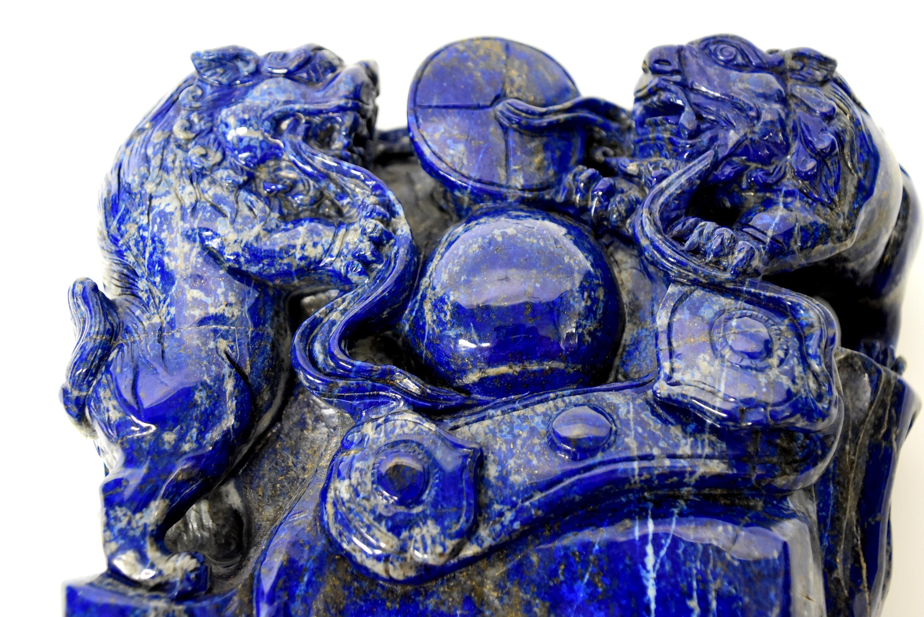The bluest of blue found in this genuine, natural lapis lazuli original block. A pair of lions flank a good fortune ball under a coin medallion and a silver tael, above a Ruyi scepter, symbolizing stability of good fortune and great wealth. The