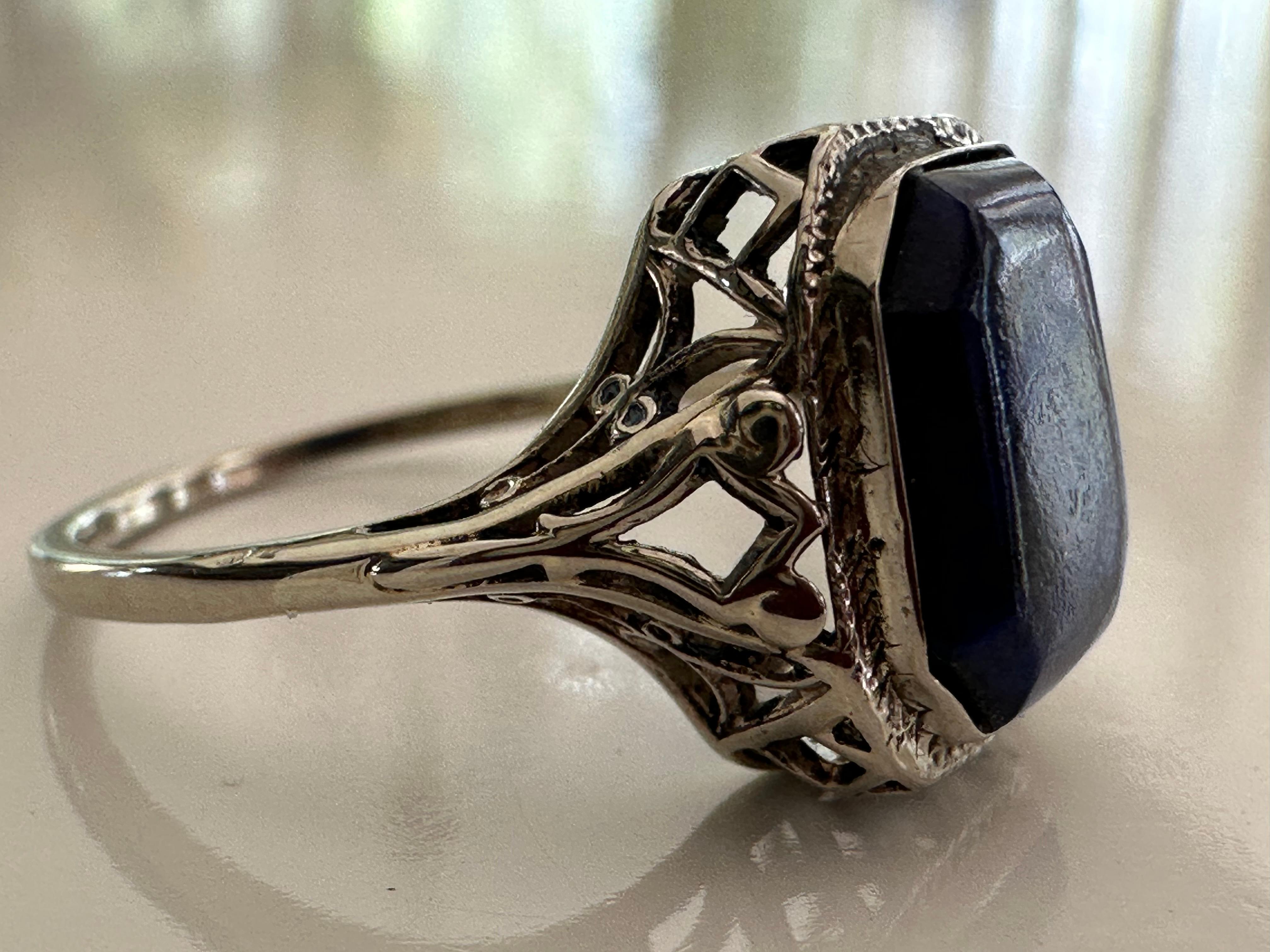 Crafted in the 1940s, this ring features a carved natural lapis lazuli set in a 14K white gold filigree band. The lapis lazuli measures approximately 10.5x 8.5mm. 