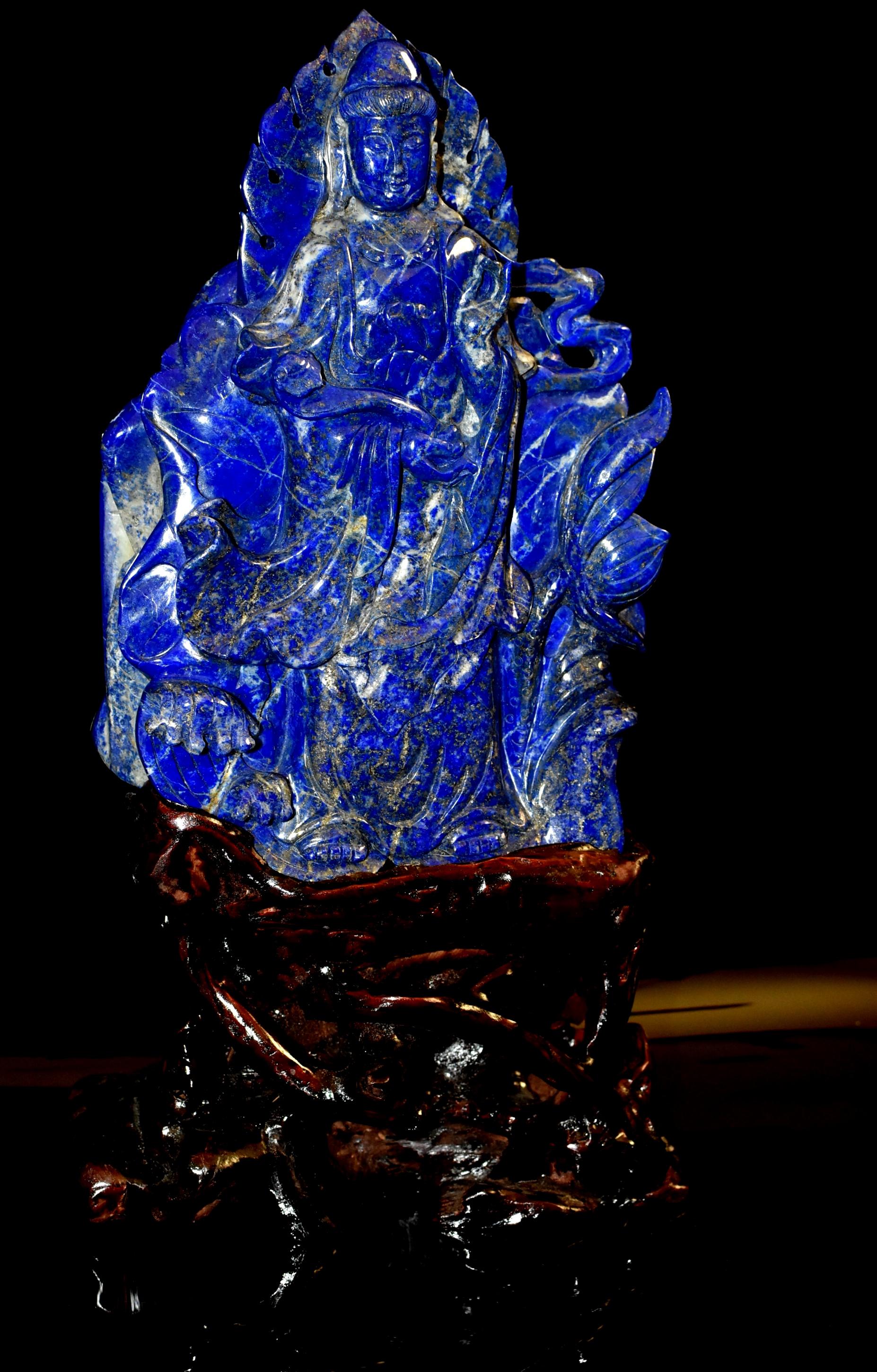 A rare, hand carved, masterpiece natural fine grade lapis lazuli Kwan Yin sculpture. Kwan Yin has an oval-shaped face with arched eyebrows and downcast eyes casting a serene aura, framed by long-lobed ears and an ushnisha covered under a hood as