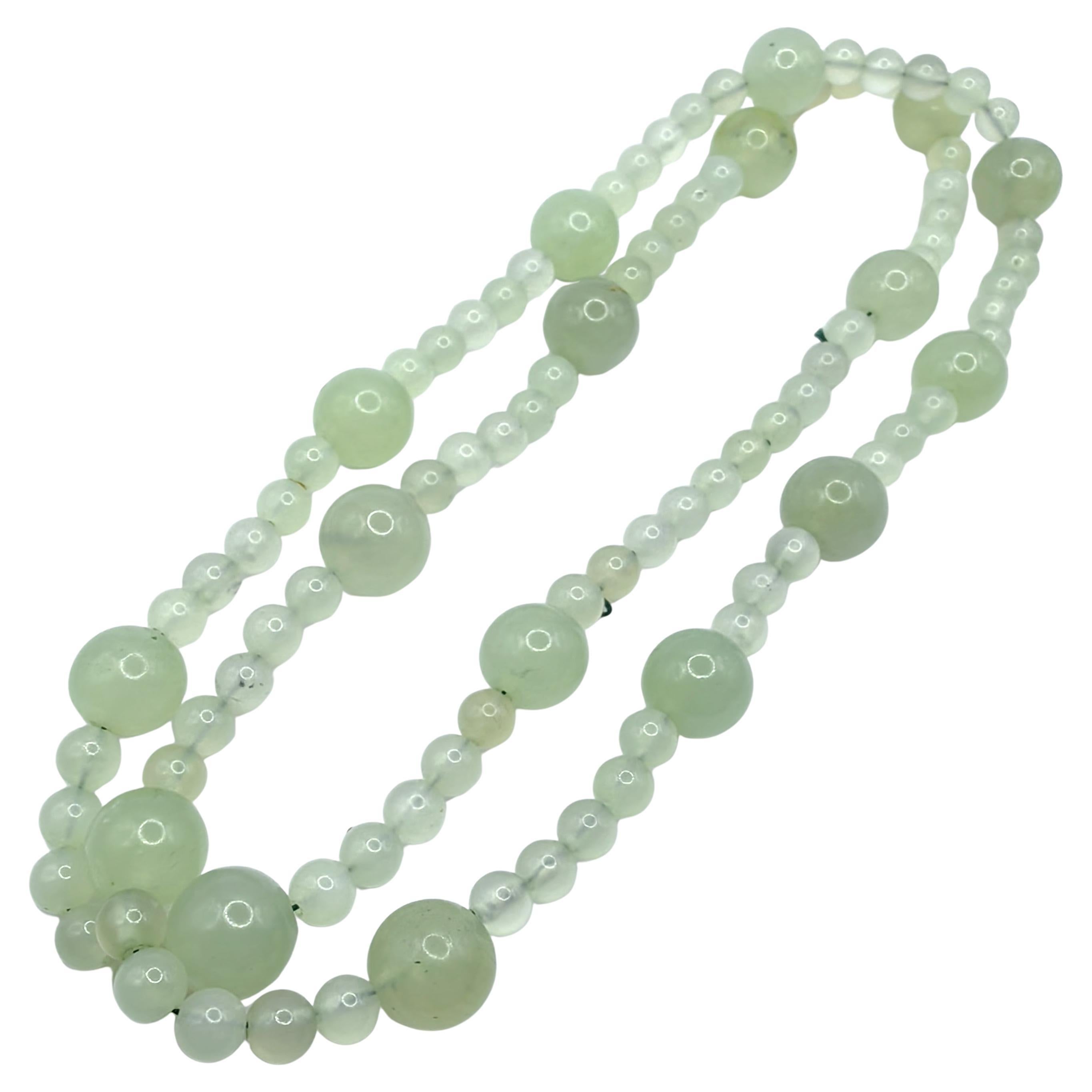 Questa straordinaria collana lunga come un'opera presenta una giada serpentina verde chiaro naturale in un sofisticato design a filo unico. Il pezzo presenta un'accurata disposizione di perline di due dimensioni: 17 perline più grandi di 13-14 mm di