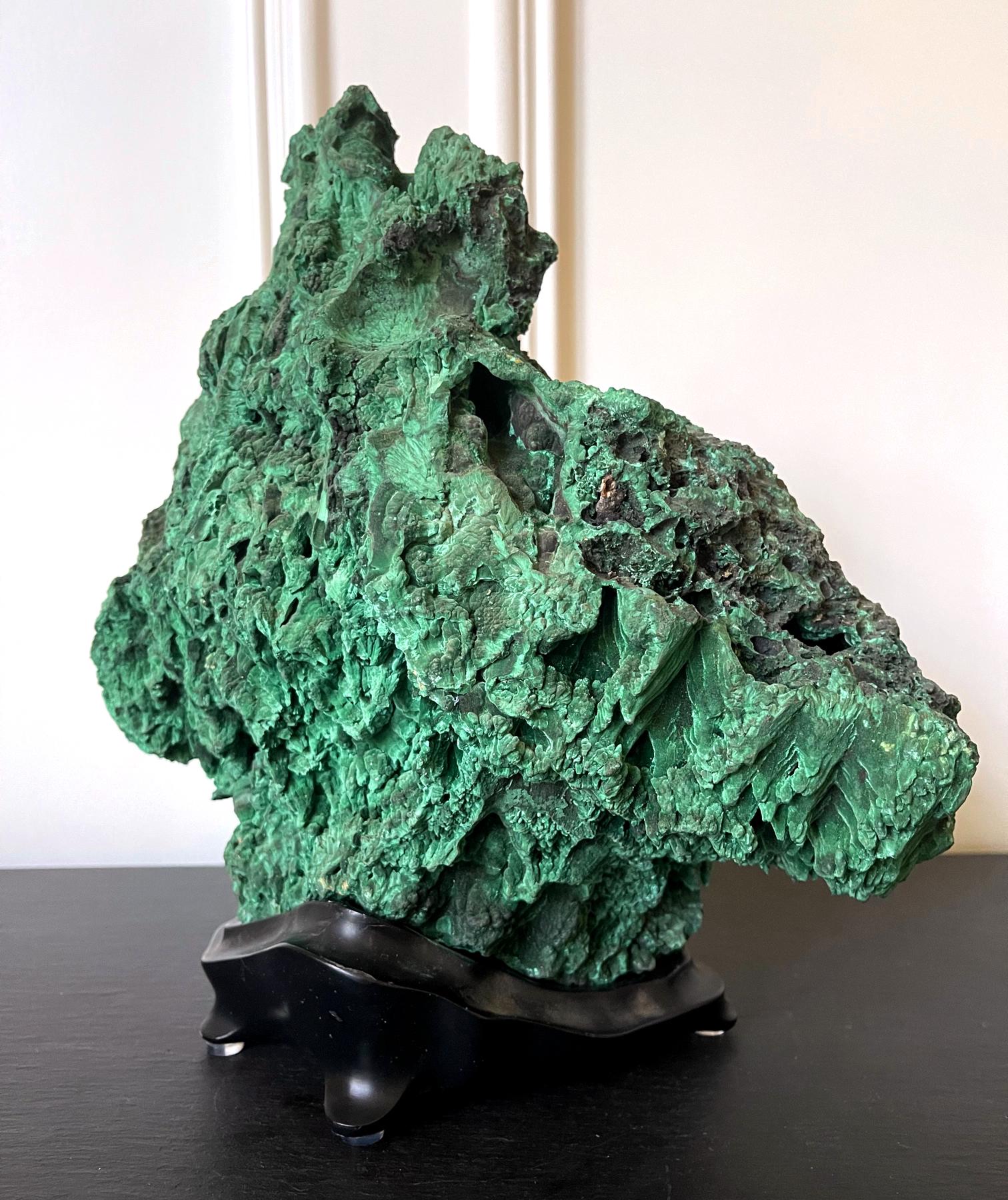 A natural malachite stone on a fitted wood stand displayed as a Chinese scholar stone (Gong Shi), also known as meditation stone. The natural specimen displays a wonderful mountainous form with a peak in the center, organic and well balanced. The