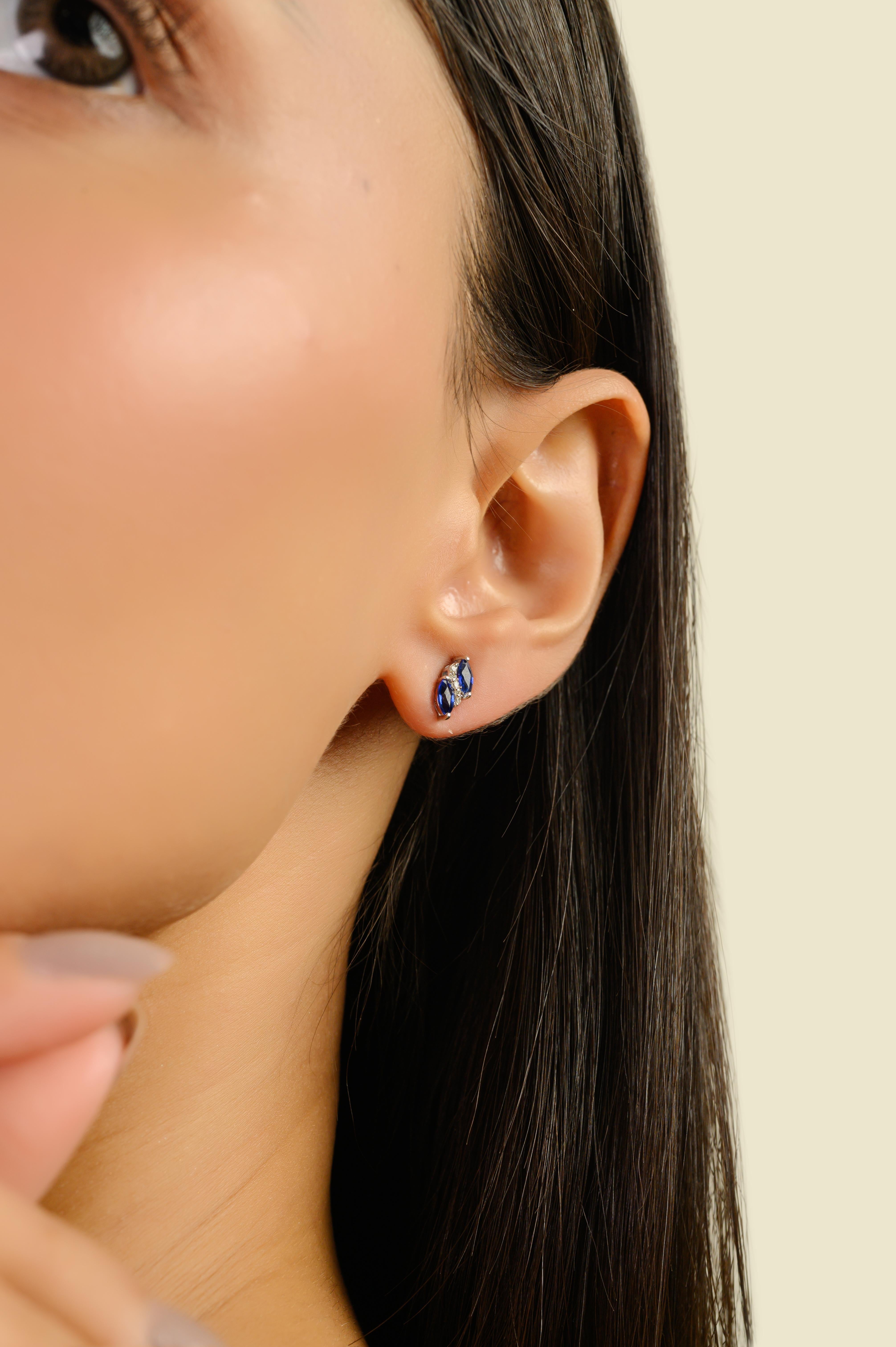 Ces élégantes boucles d'oreilles présentent 4 saphirs bleus naturels taille marquise totalisant 0,63 carats, chacun mesurant environ 4x2,3 mm, sertis en or blanc 14 carats. Les saphirs sont entourés de 10 diamants ronds de taille brillant totalisant