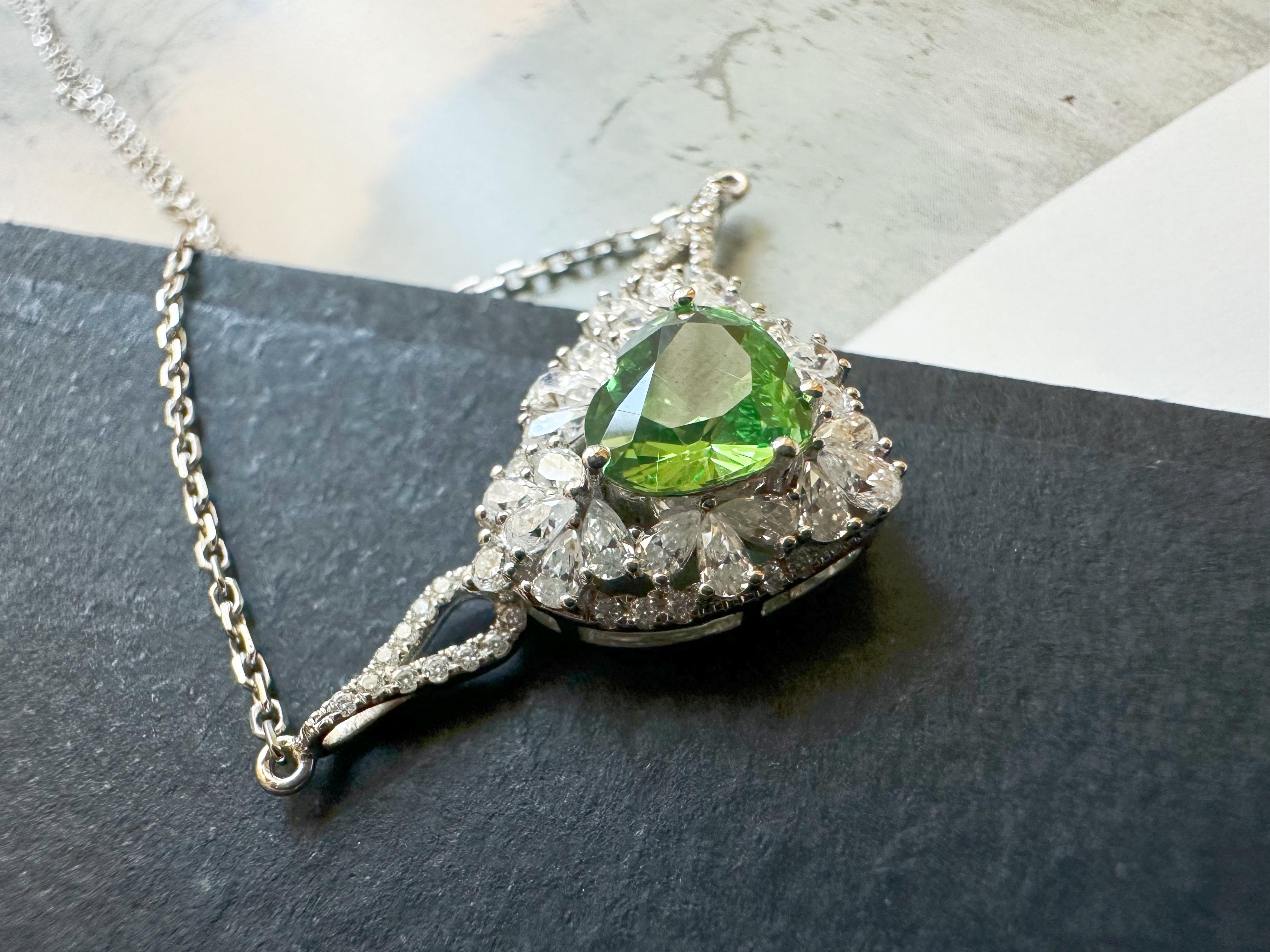 This exquisite Tsavorite pendant is an authentic one-of-a-kind statement piece. Crafted from radiant mint green Tsavorite, the pendant is artfully accented with a delicate cluster of shimmering moissanite stones. The heart-shaped design is elegantly