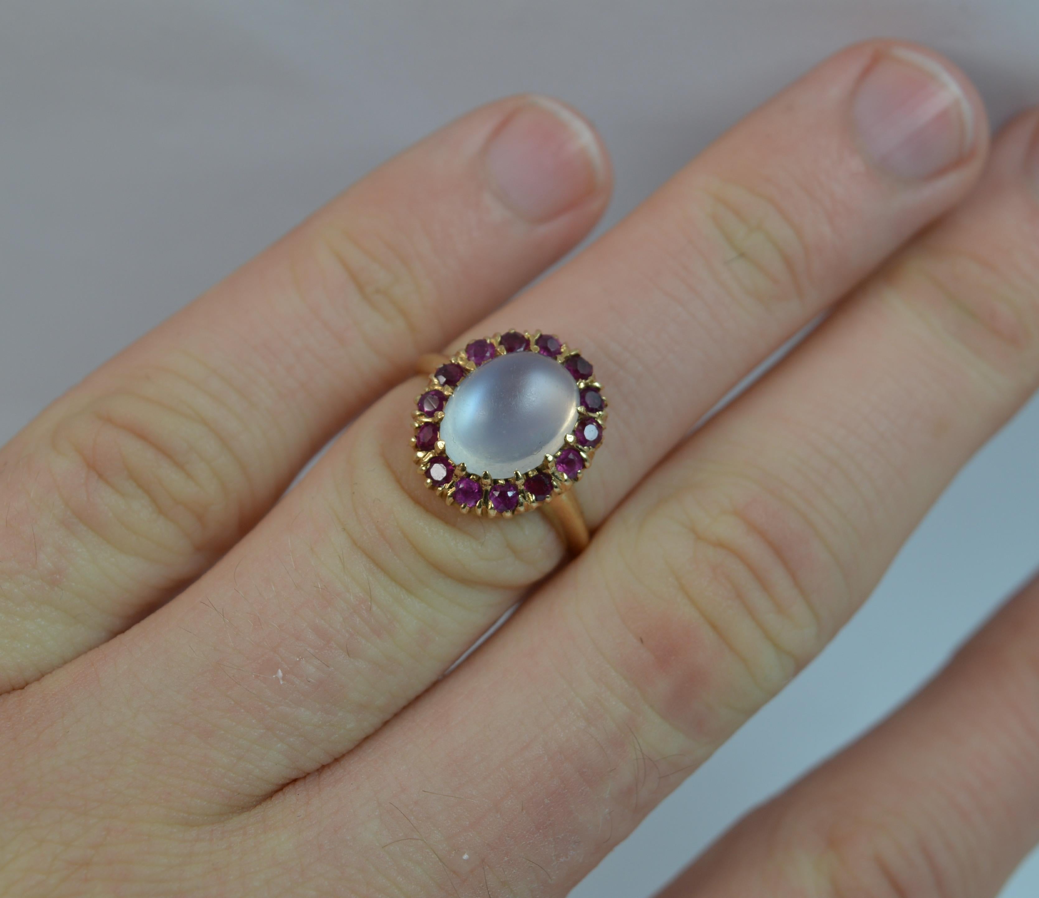 
A beautiful ladies cluster ring in 14 carat yellow gold.

Set with a natural sugarloaf moonstone to the centre, 8mm x 10mm. 

Surrounding the moonstone are fourteen natural rubies to form a cluster head to measure 12mm x 14.5mm.

Protruding 8mm off