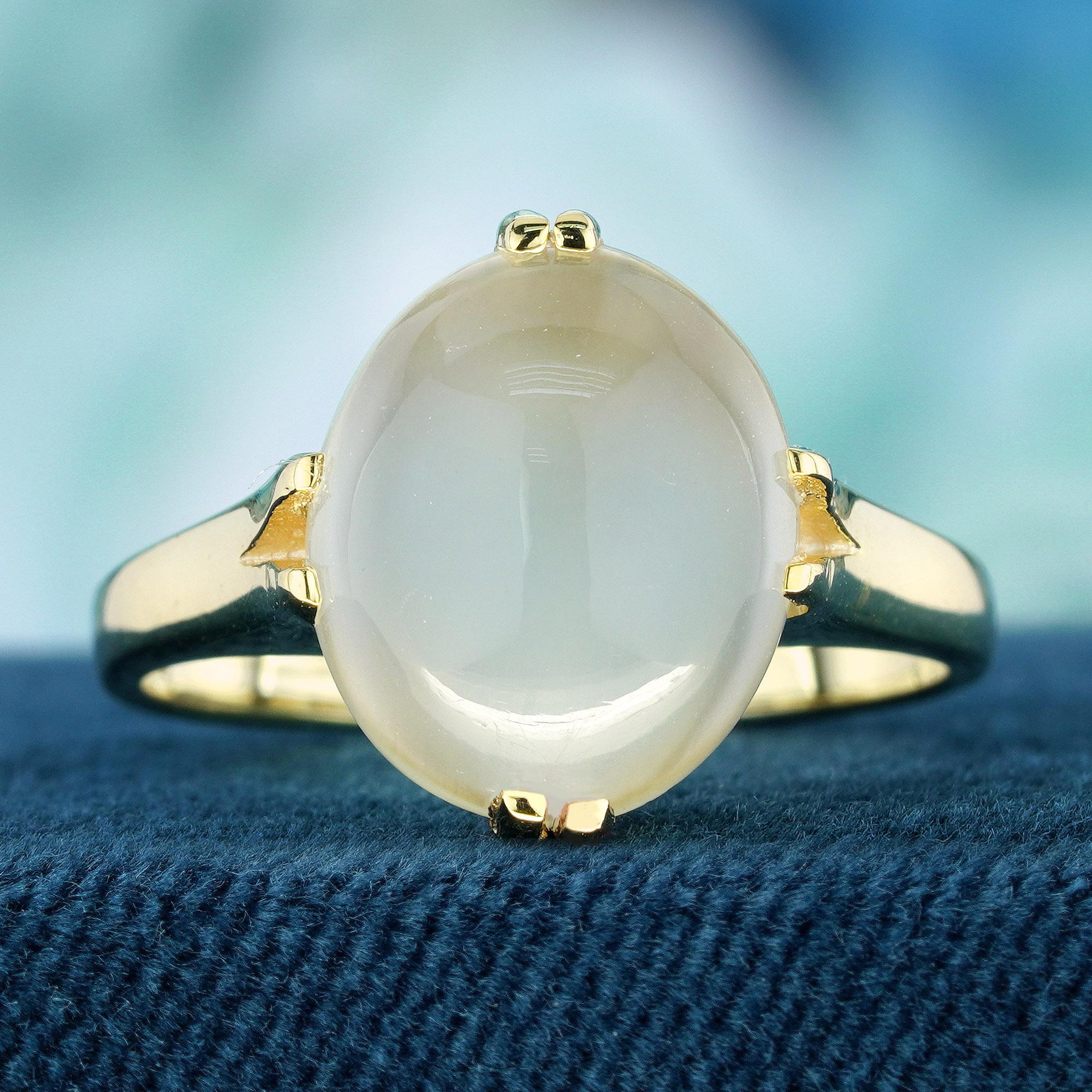 Cette bague de style vintage présente un solitaire en pierre de lune blanche naturelle en forme de cabochon, étonnamment positionné en son centre. L'éclat unique de la pierre précieuse est mis en valeur par le design de la tige fendue du bracelet en