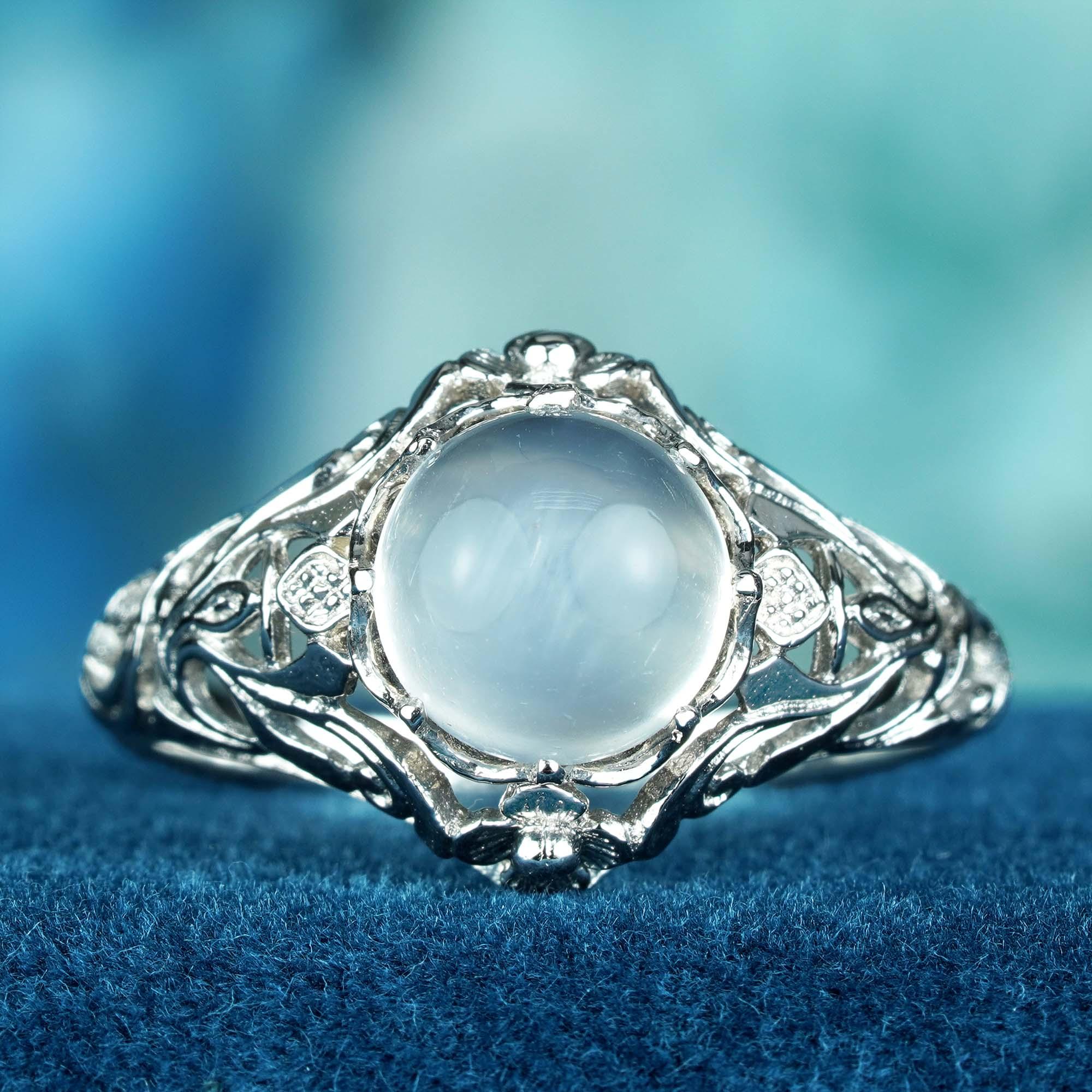Voici un trésor d'une époque révolue, au clair de lune. Cette bague exquise brille de l'éclat éthéré d'une pierre de lune naturelle, sa surface laiteuse captant la lumière et dansant d'une luminescence intérieure. Entouré d'une toile de filigrane,